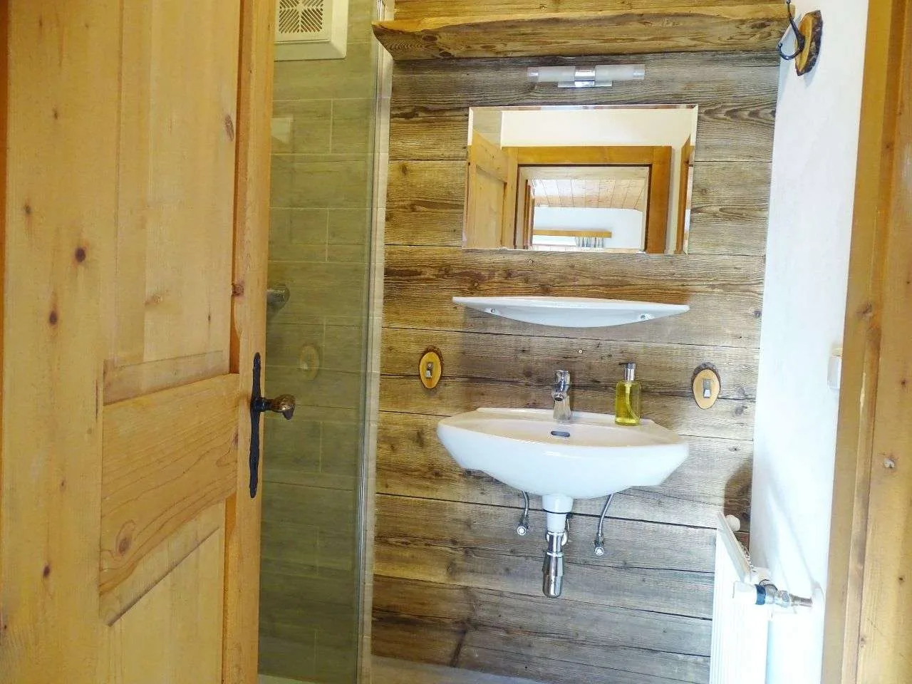 A bathroom sink and mirror are set against a wood-paneled wall.