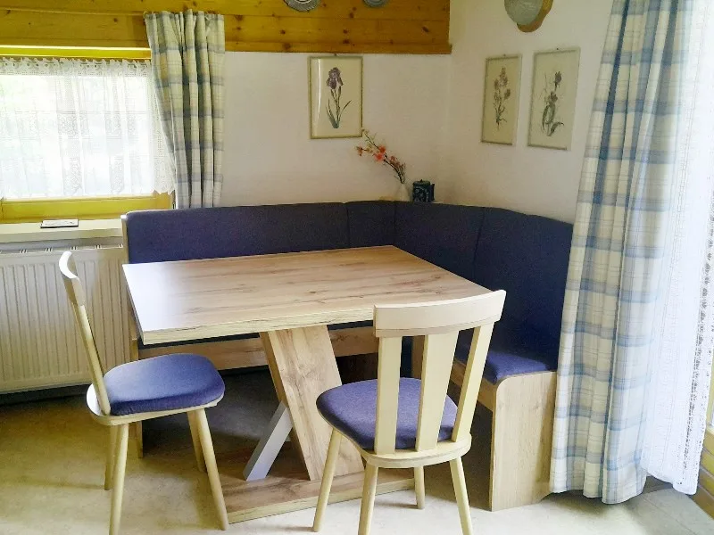 A dining nook with a wooden table, chairs, and built-in seating.