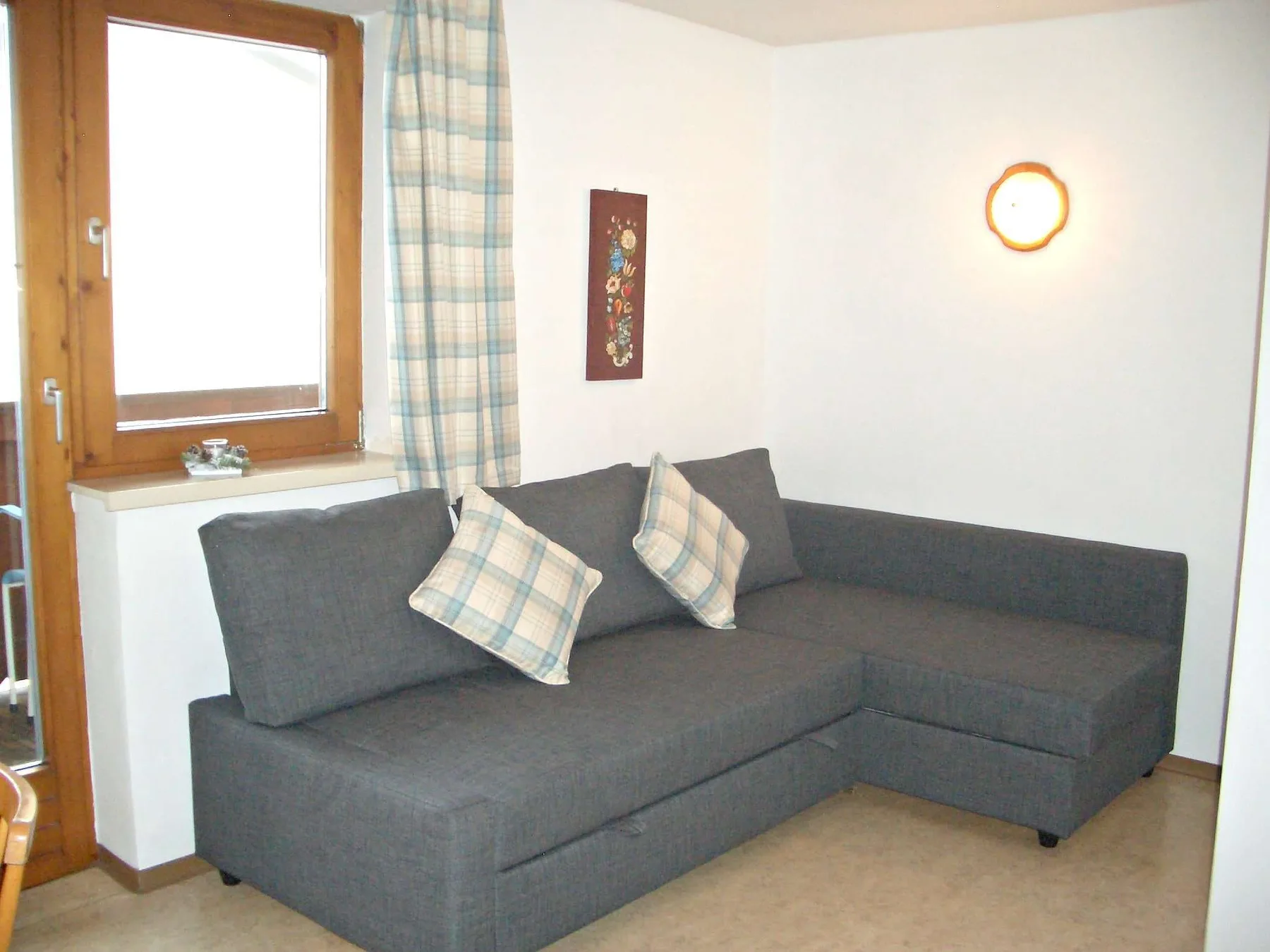 A living room with a dark sectional sofa and plaid cushions.