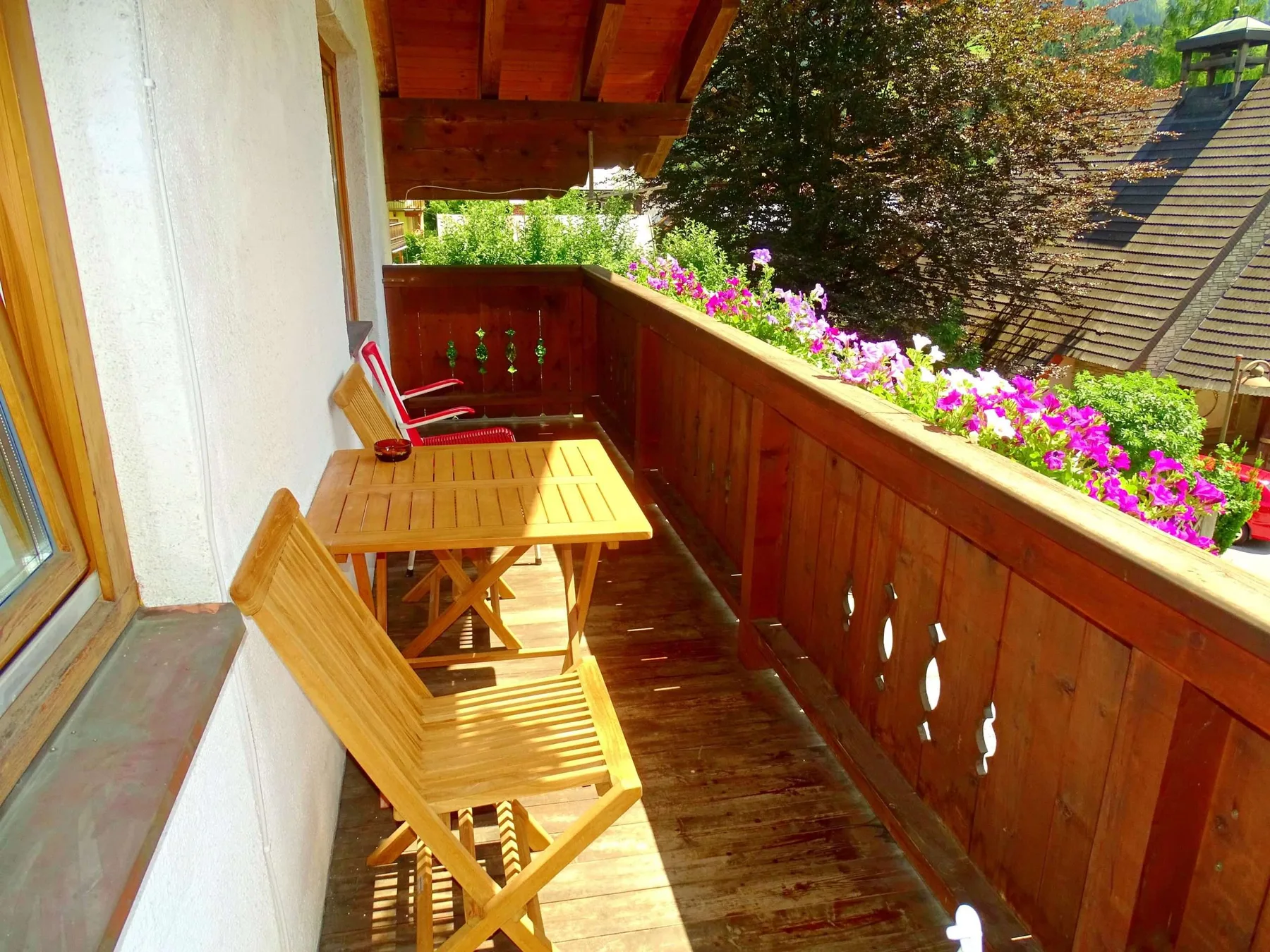 A wooden balcony with seating and a flower box along the railing.