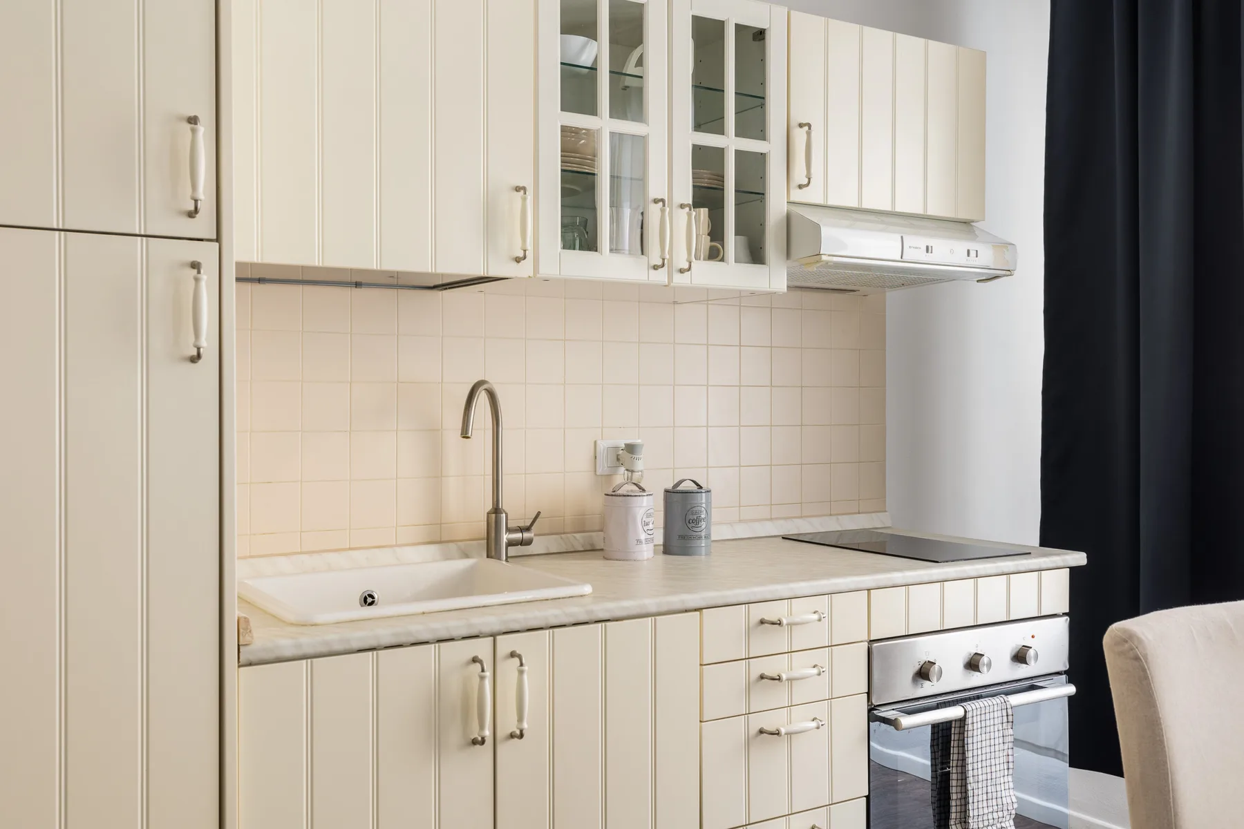 A bright kitchen with cream cabinetry, a tiled backsplash, and a countertop.