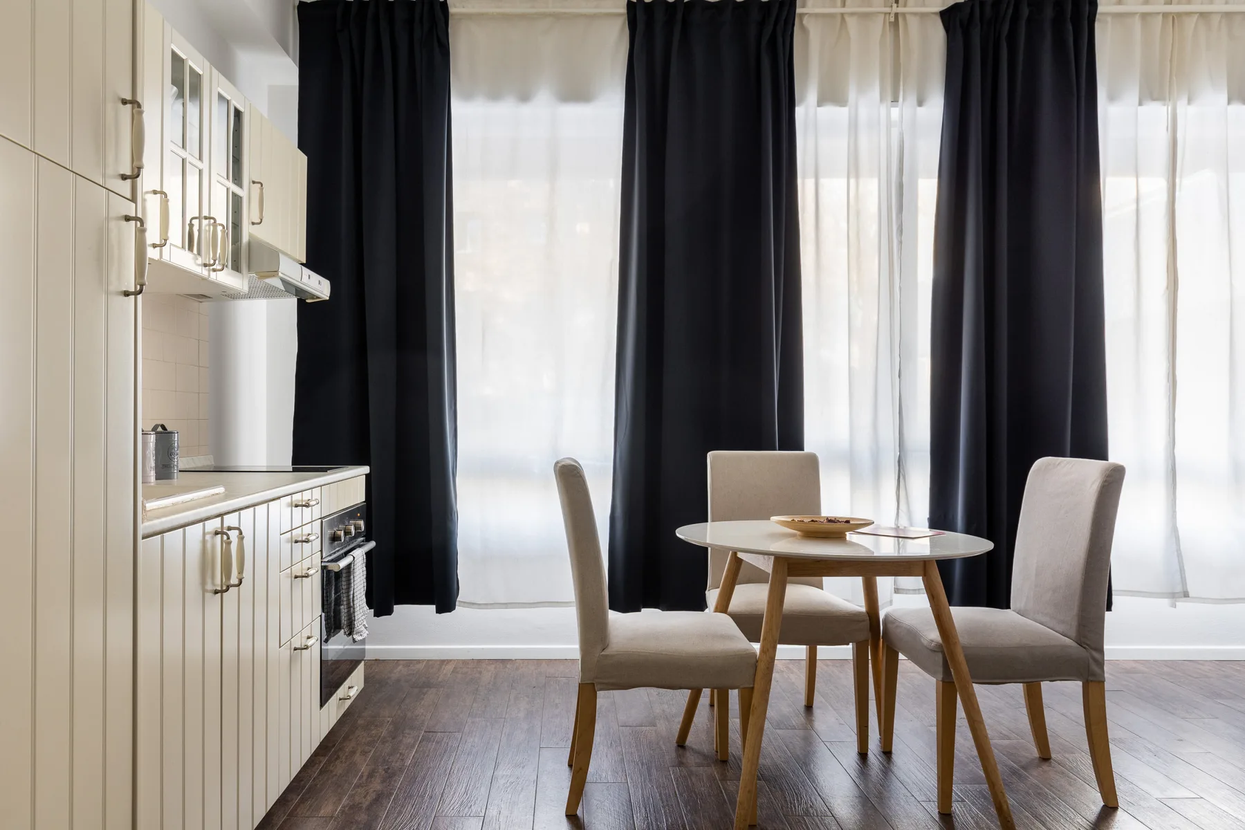 A dining area with a round table and seating beside a kitchen.