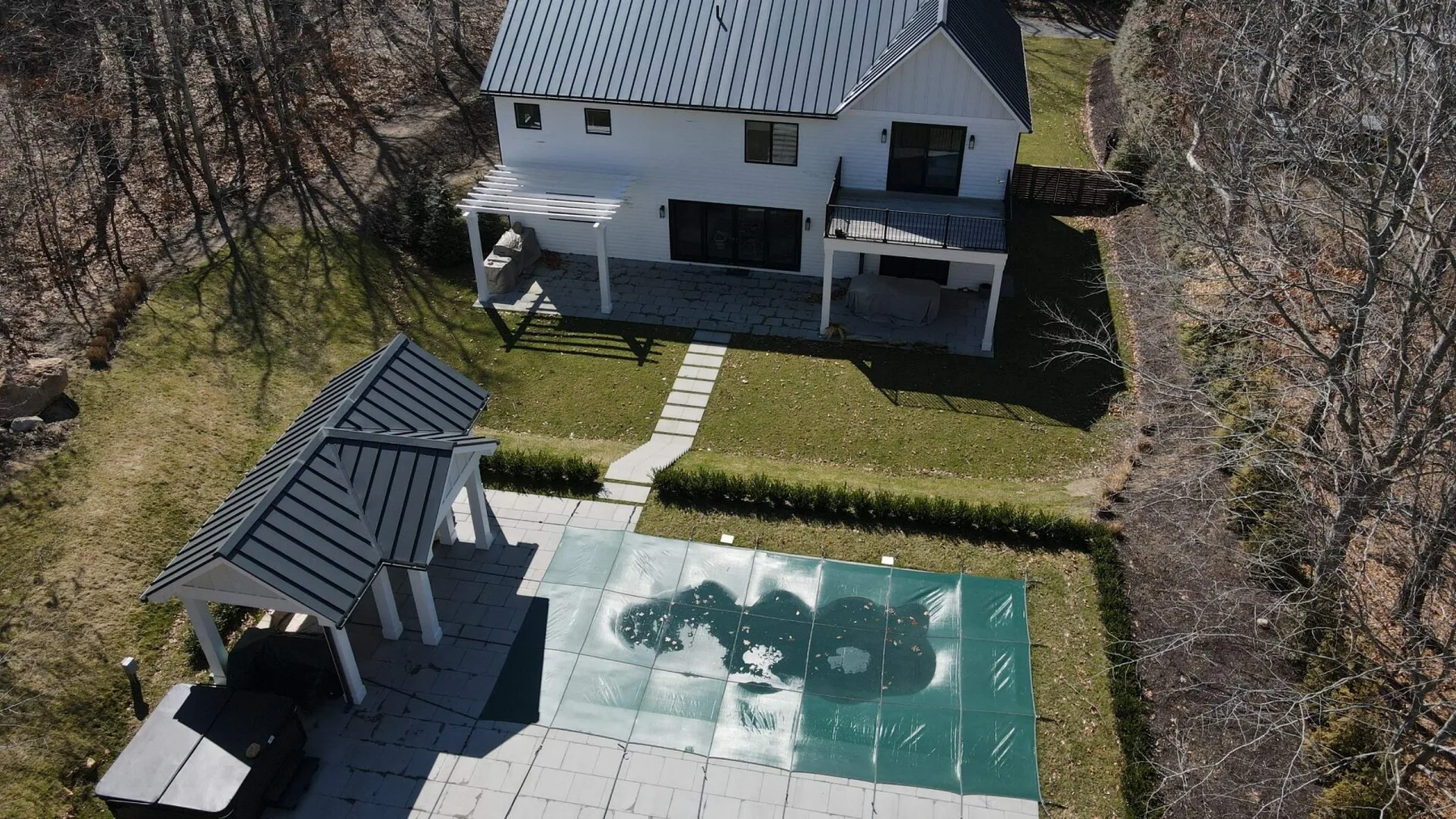 Una vista aérea muestra una casa, una piscina rectangular y un pequeño patio techado.