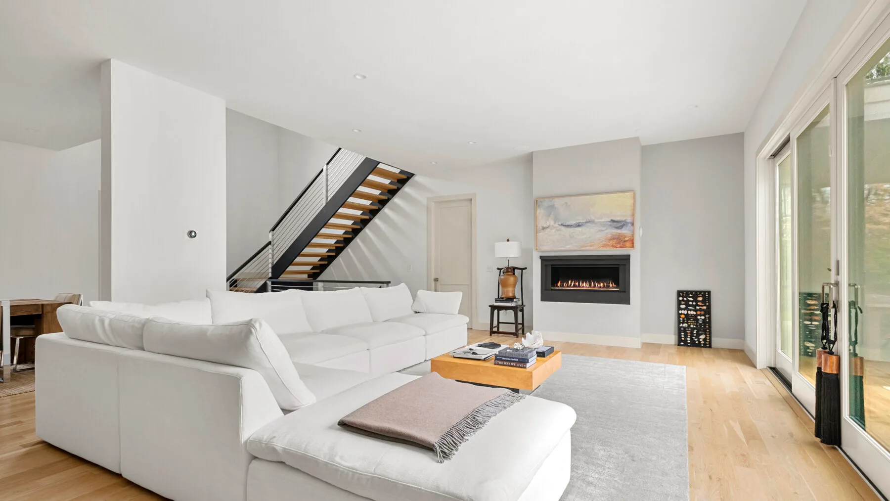 Una sala luminosa con asientos blancos, una chimenea y grandes puertas de vidrio.
