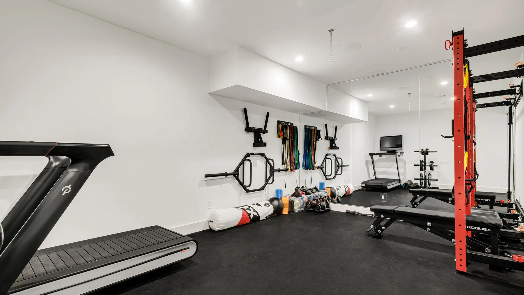 Un gimnasio con equipo de ejercicio, una cinta de correr y un banco de pesas.