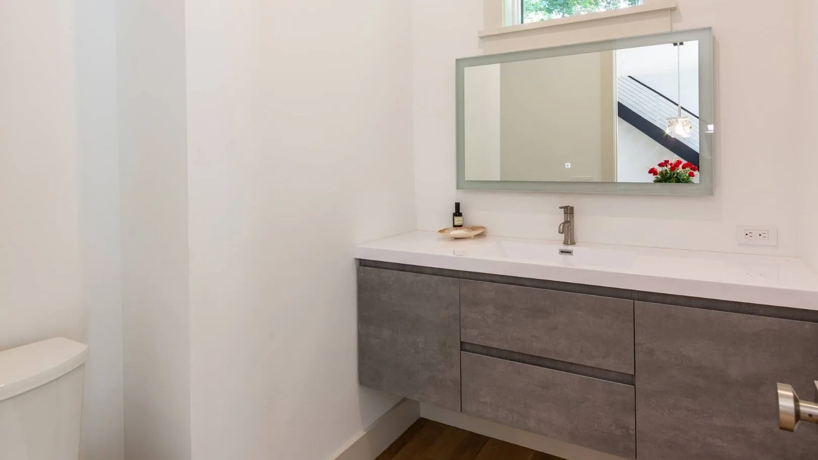 Un baño luminoso con un amplio lavabo, fregadero y espejo de pared.