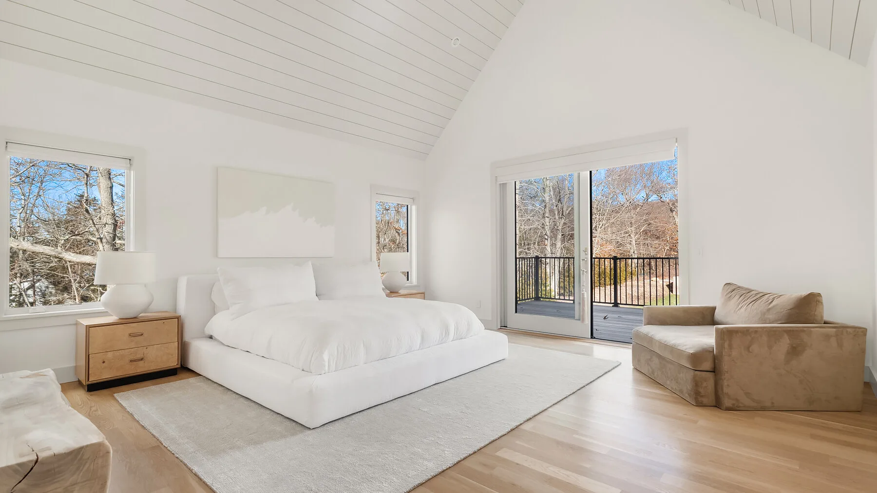 Un dormitorio luminoso con una cama grande y puertas corredizas de vidrio hacia un balcón.