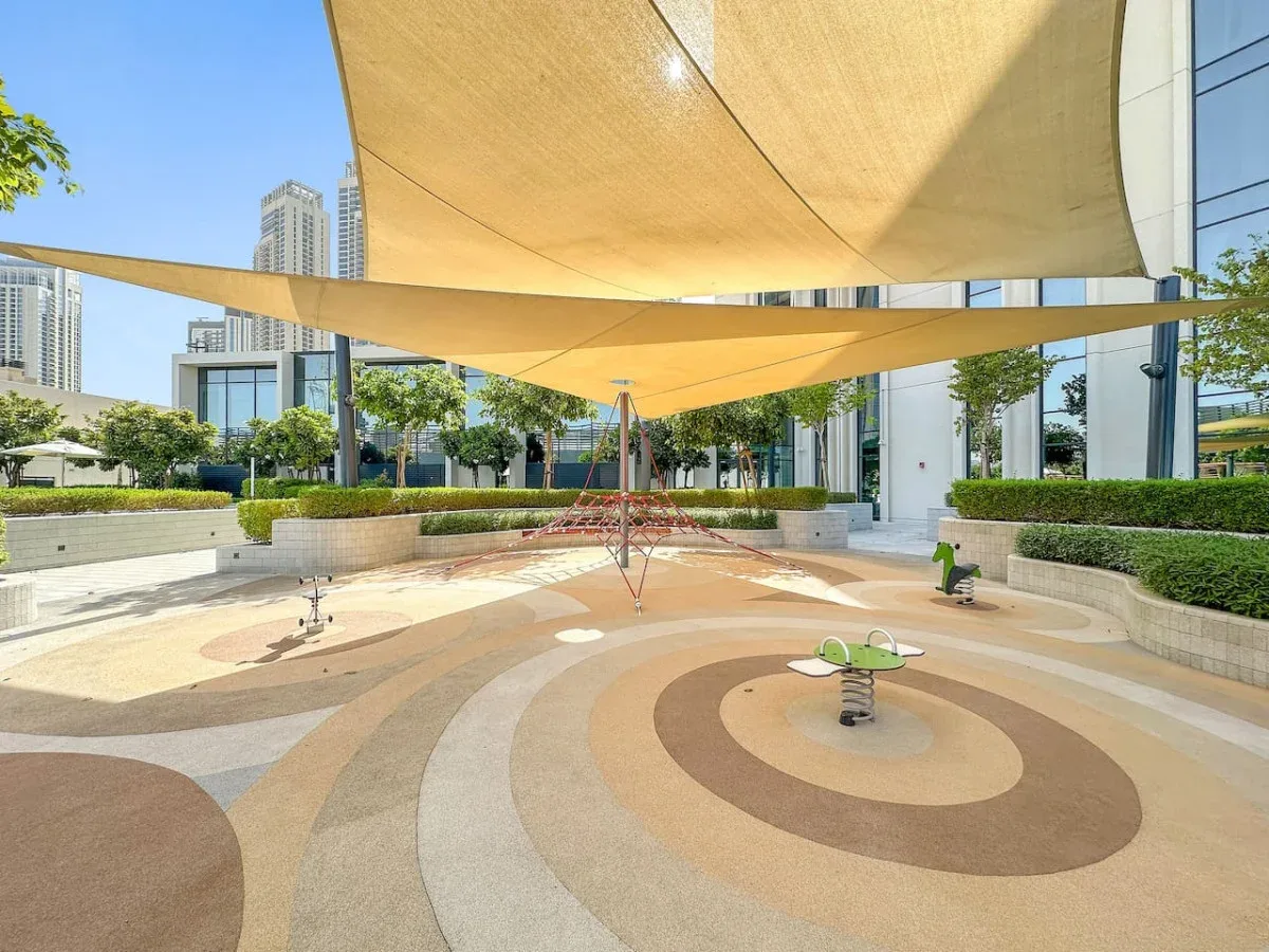 Un patio al aire libre tiene pavimento estampado y grandes toldos de sombra.