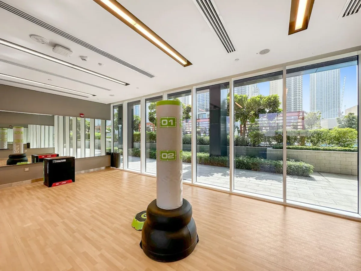 Una luminosa sala de ejercicio con un saco de boxeo junto a grandes ventanas.