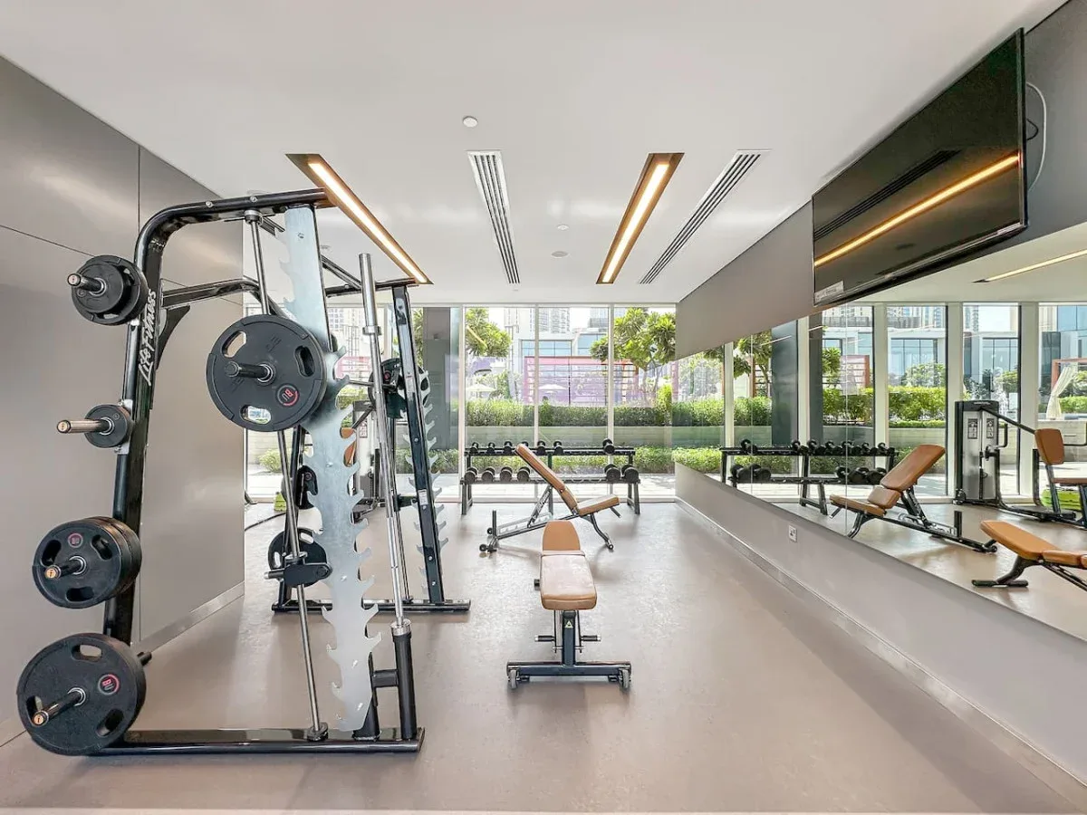 Un gimnasio con equipo de pesas y paredes con espejos.