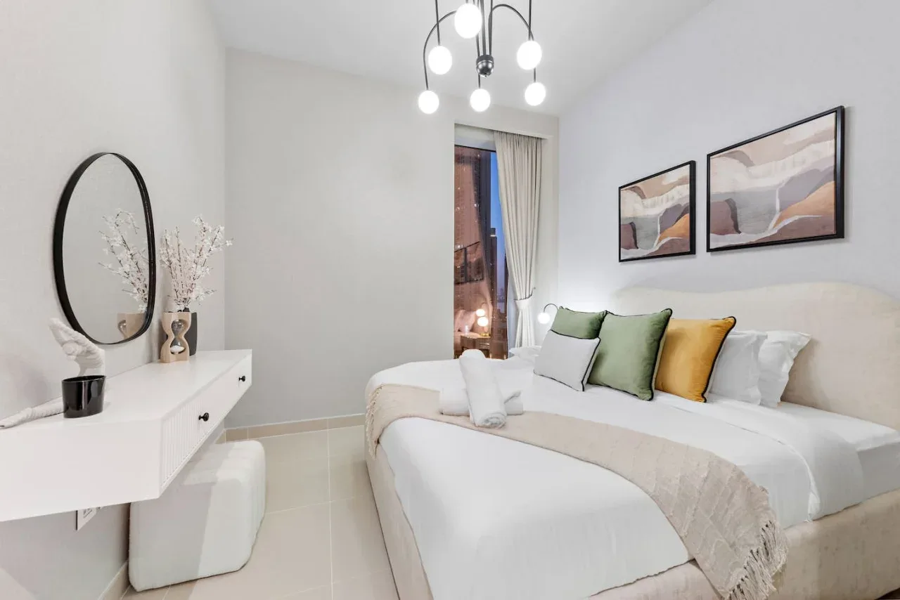 Un dormitorio luminoso con una cama bien tendida y cojines decorativos de colores.