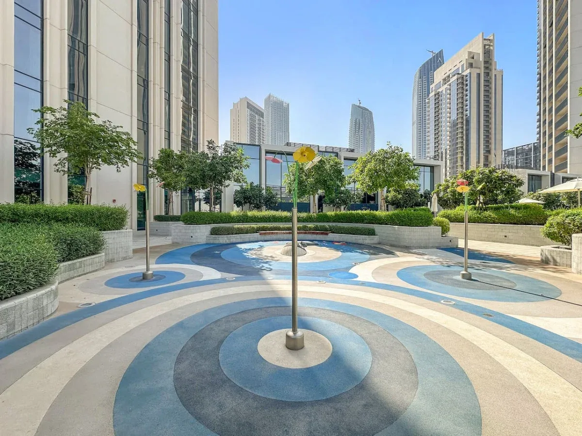 Un patio ajardinado con una zona pavimentada circular de diseño azul y gris.
