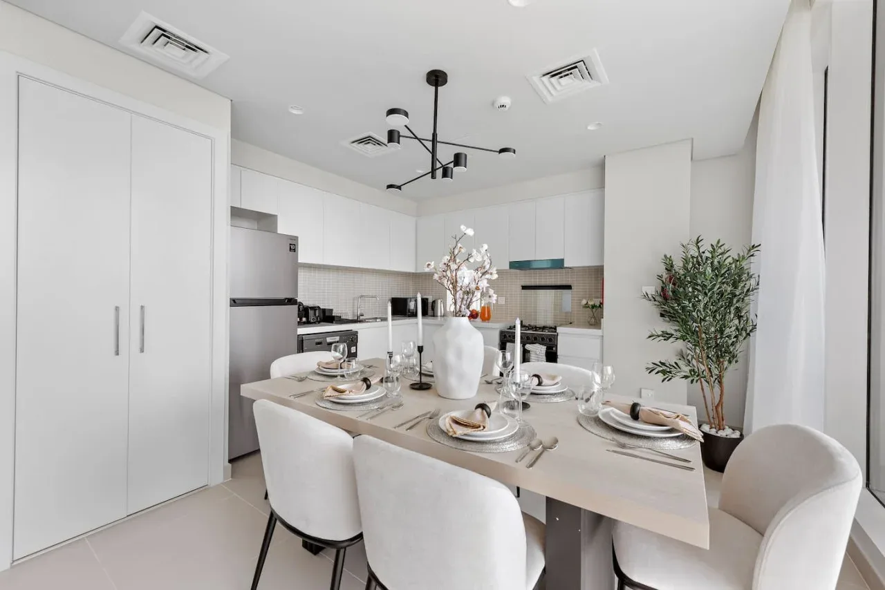 Un comedor luminoso con la mesa puesta junto a una cocina moderna.