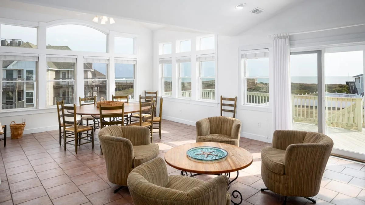 Un solárium luminoso con una mesa de comedor y asientos junto a grandes ventanas.