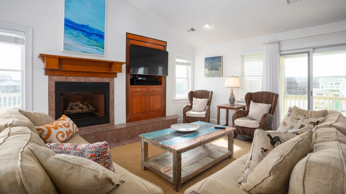 A bright living room with seating arranged around a coffee table and fireplace.