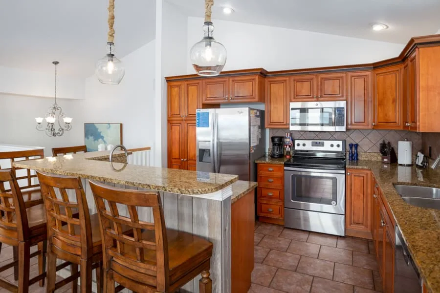 Cocina y comedor con una isla de granito y gabinetes de madera.