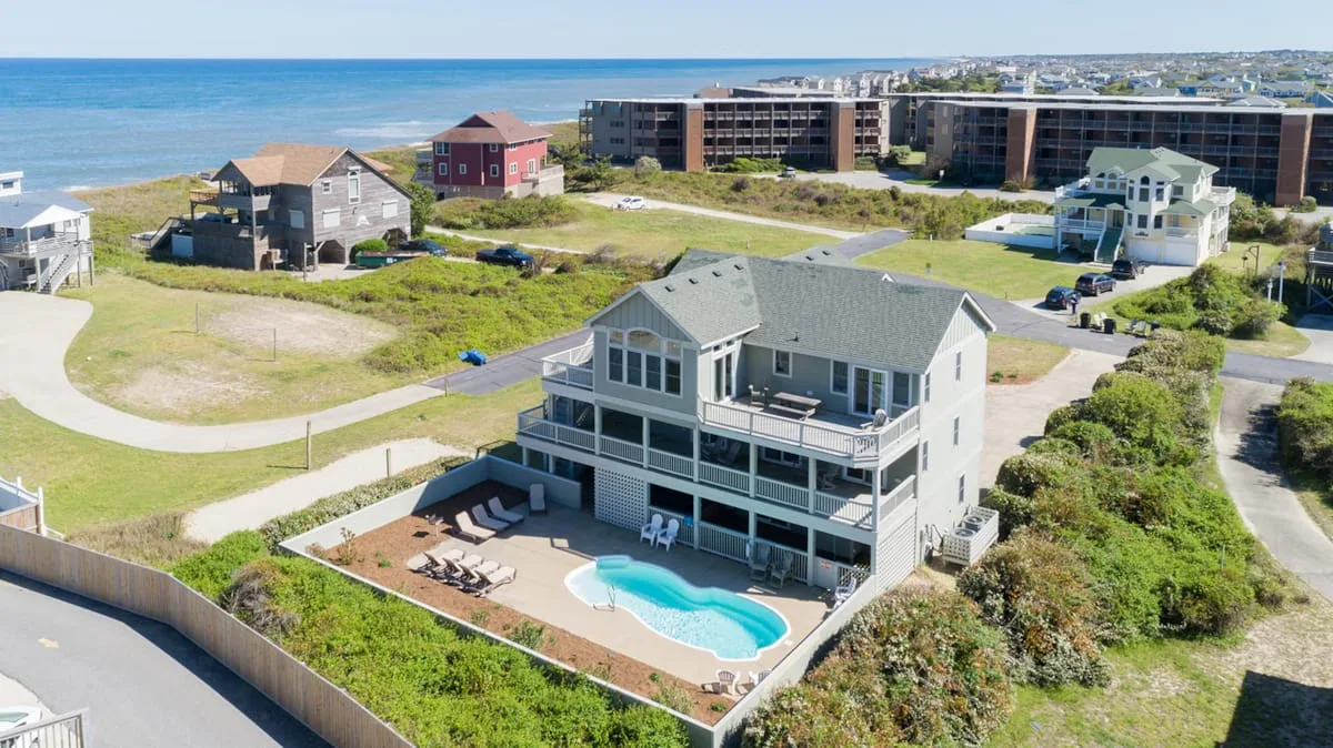 A coastal house with a pool and patio sits near the shoreline.