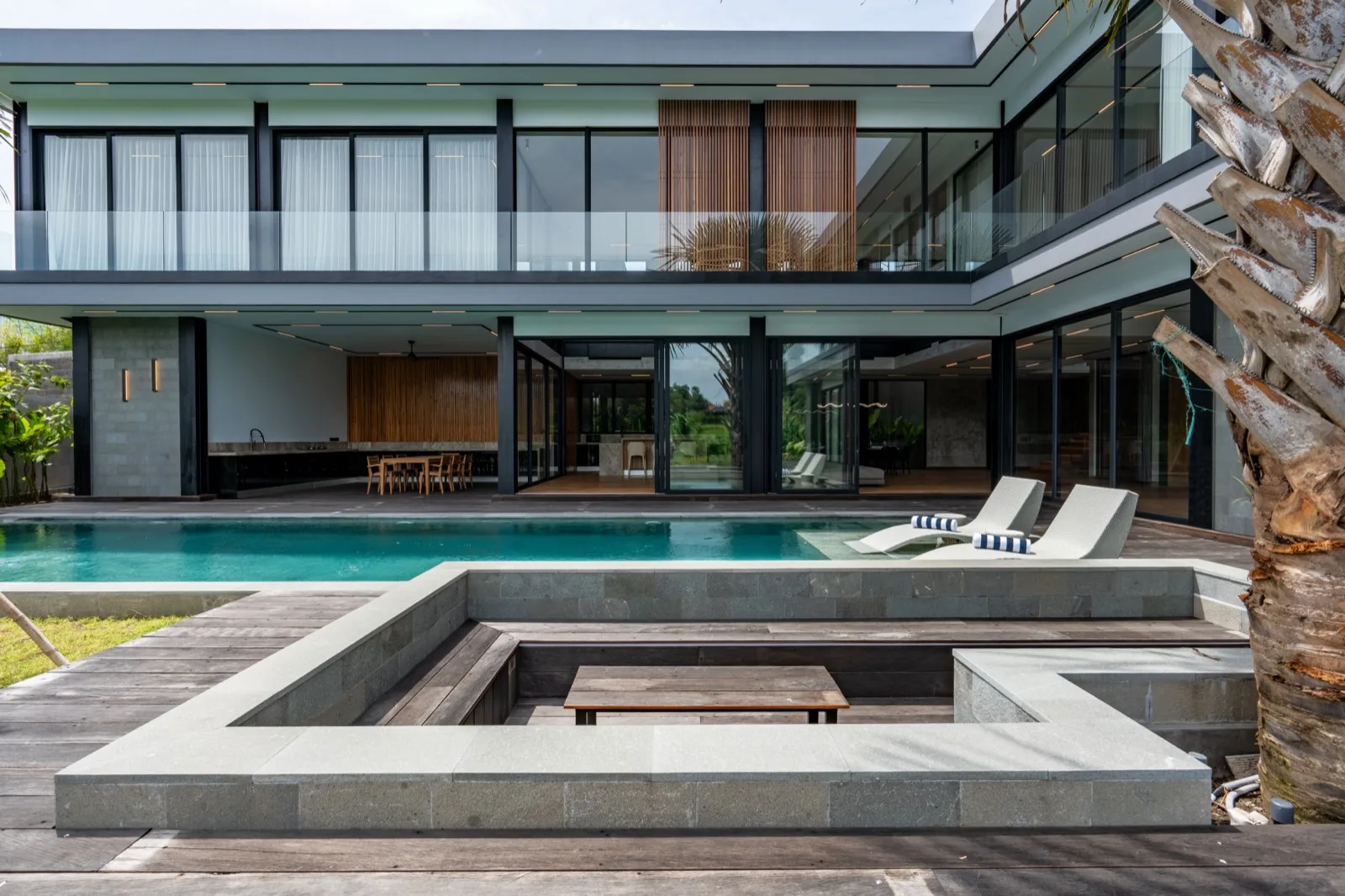Una casa moderna se abre a una piscina y una zona de estar hundida.