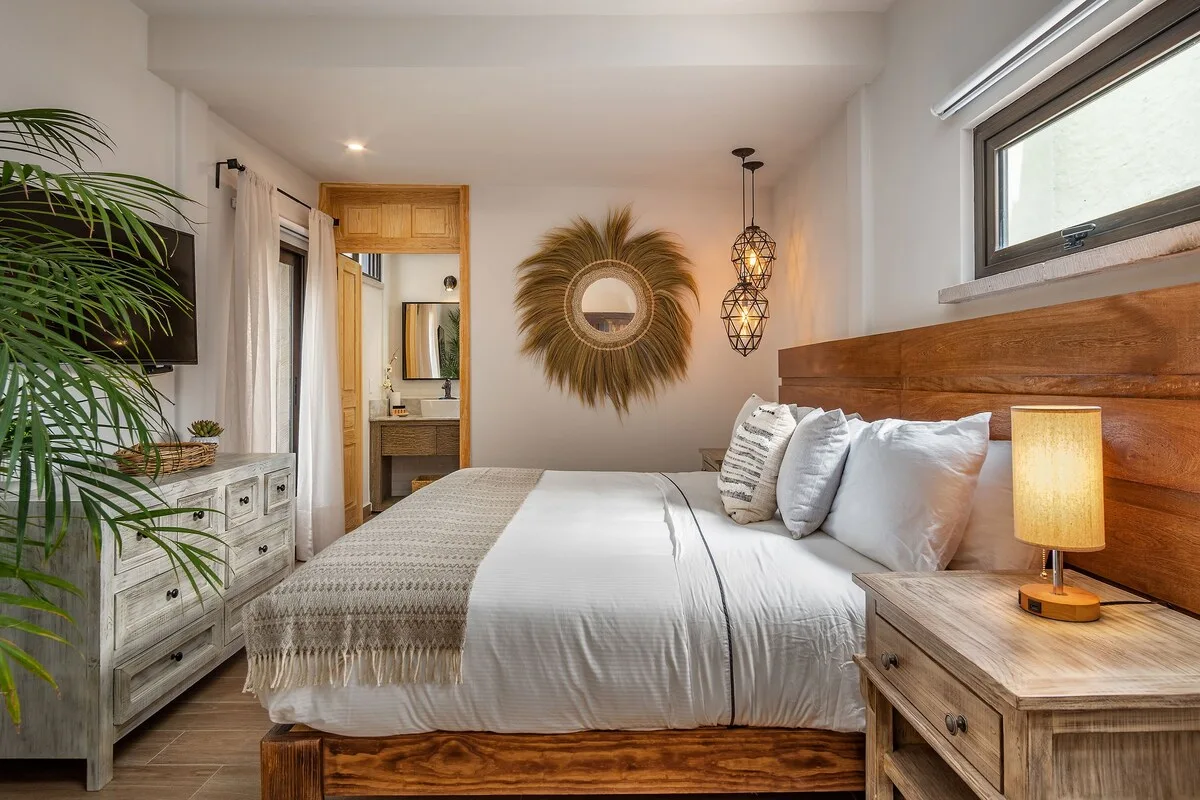 Un dormitorio con una cama bien tendida y una mesita de madera.