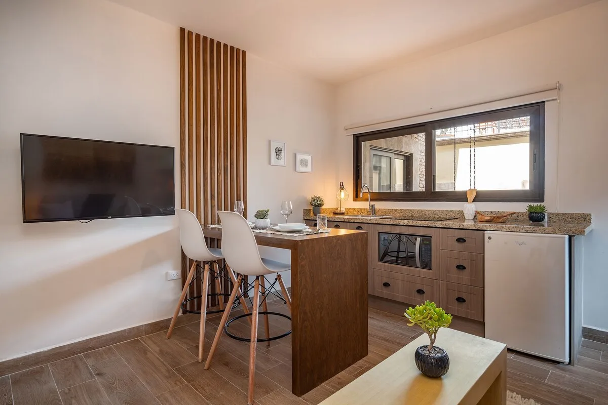 A compact kitchen with a counter, stools, and a large window.