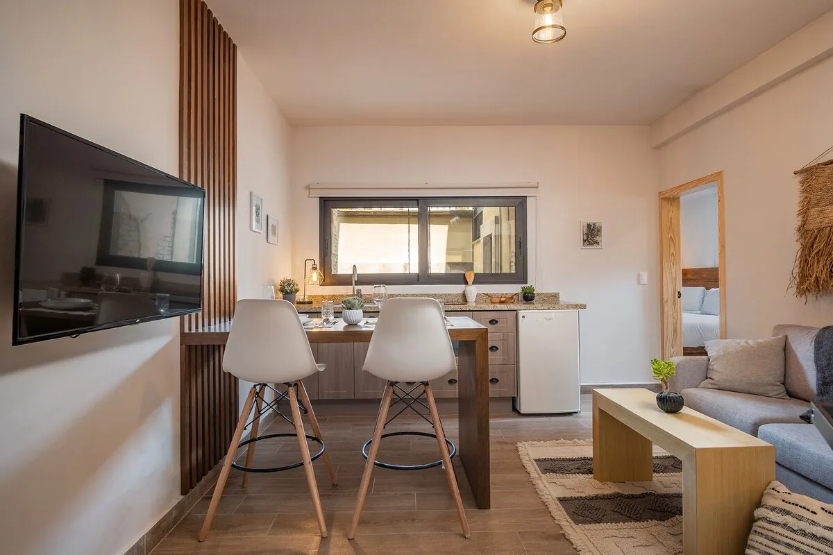 Una luminosa sala de estar diáfana tiene una mesa de comedor, una pequeña cocina y asientos.