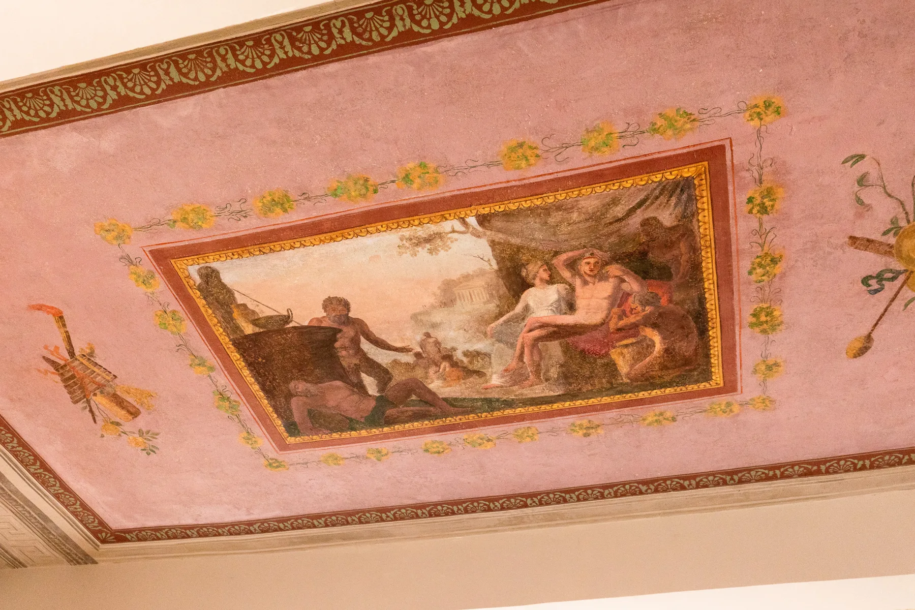 Un panel pintado en el techo muestra figuras clásicas rodeadas de decoración floral.