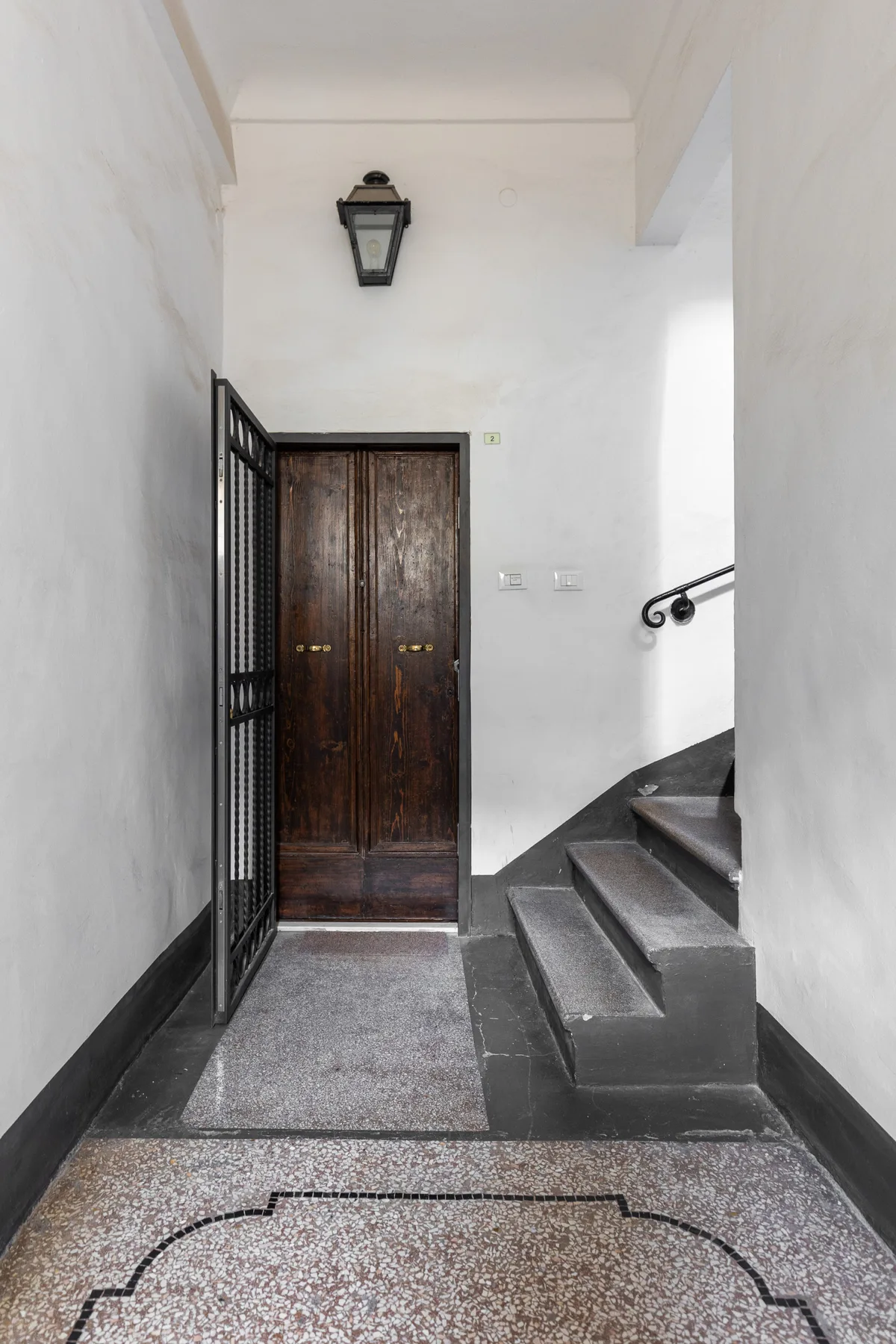 Un pasillo interior estrecho con una puerta de madera oscura y escaleras.
