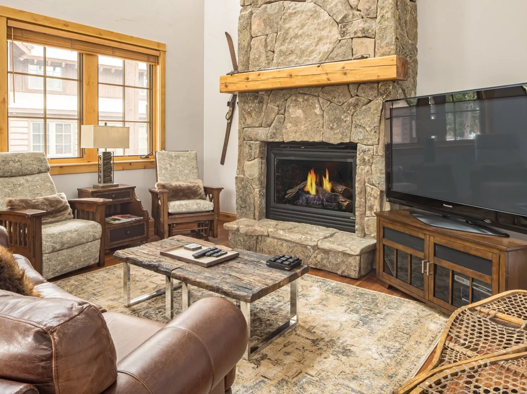 Una sala de estar con chimenea de piedra, asientos y un televisor.
