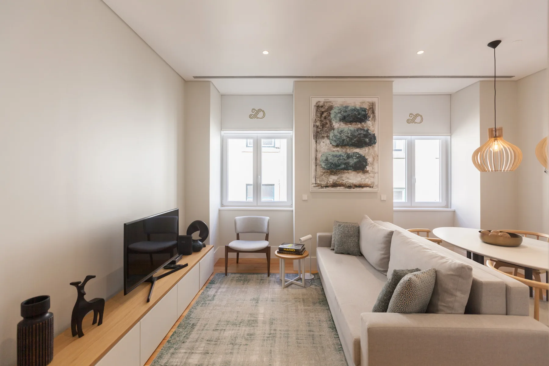 A bright living room with seating, a television, and windows.