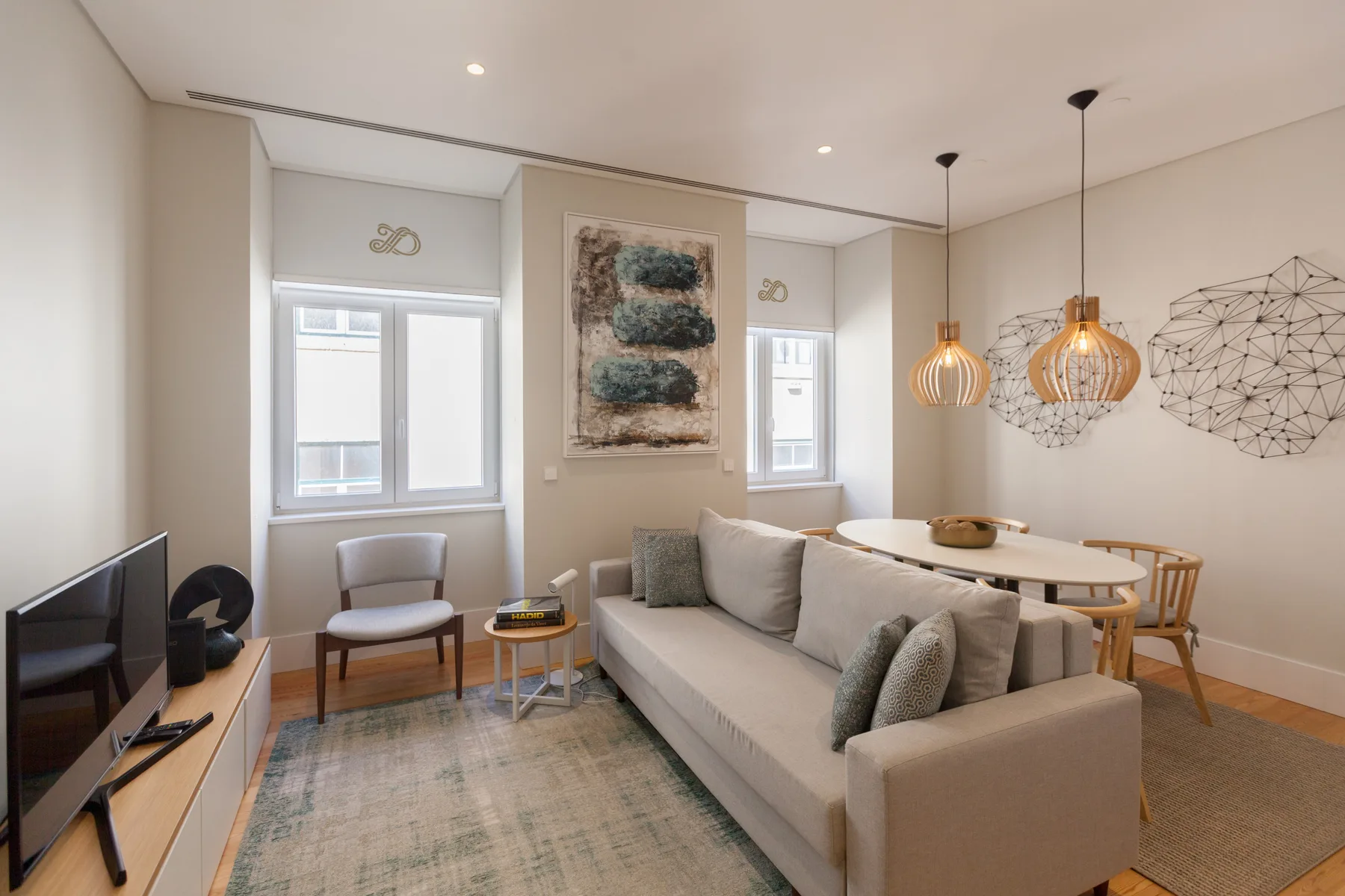 A bright living and dining area with a sofa, table, and pendant lights.