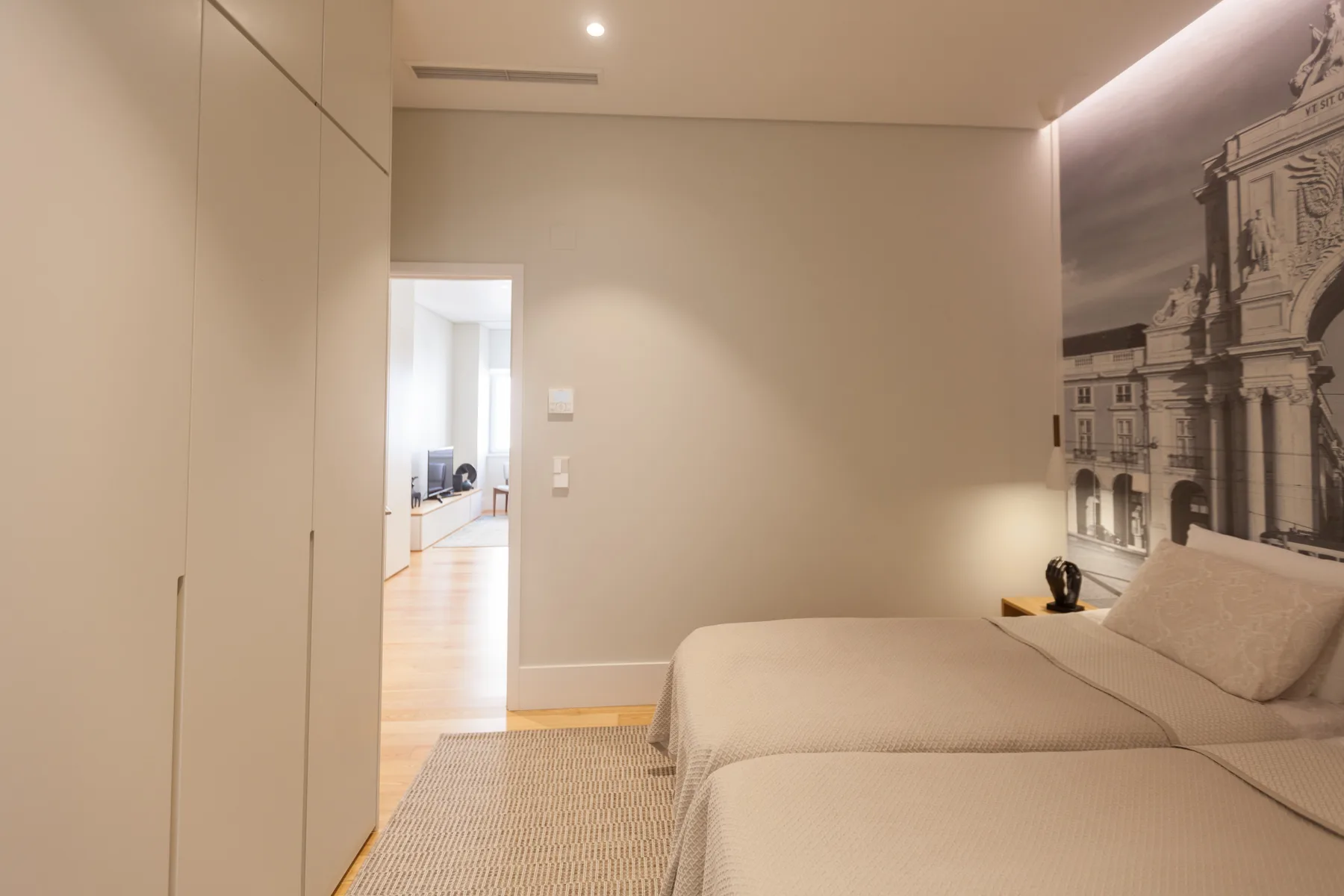 A bedroom with a bed and a large black-and-white architectural wall image.