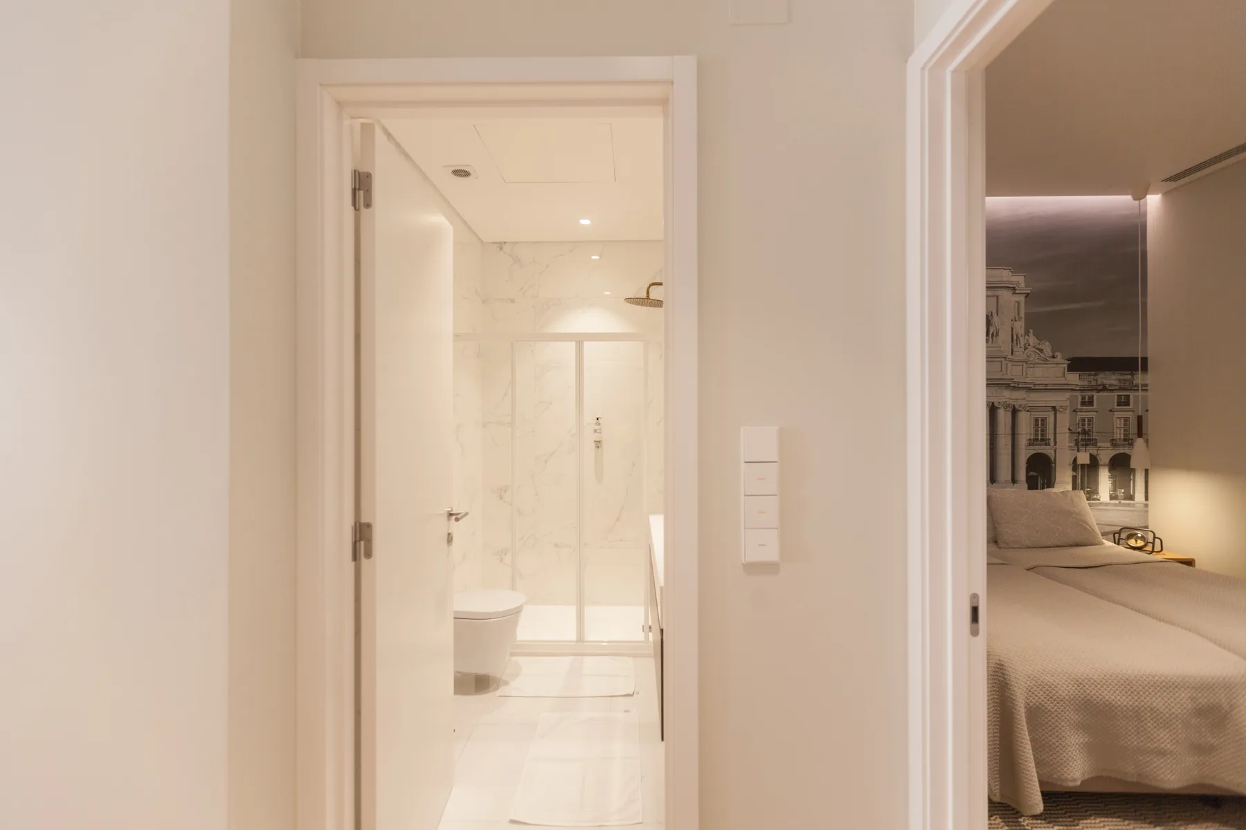 A hallway with open doorways leading to a bathroom and bedroom.