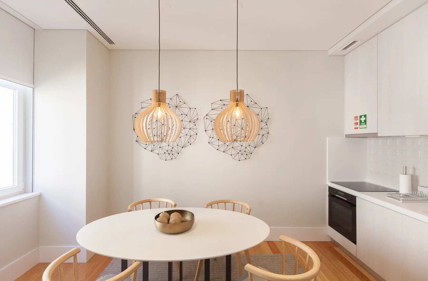 Un comedor luminoso con una mesa redonda y lámparas colgantes.