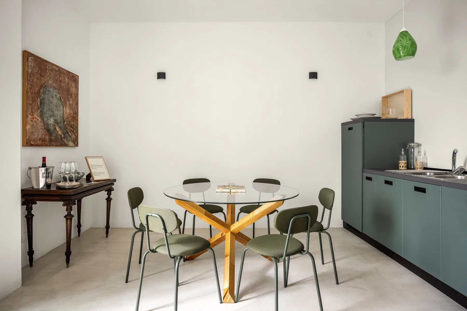 Comedor con una mesa redonda de vidrio y una cocina compacta junto a la pared.