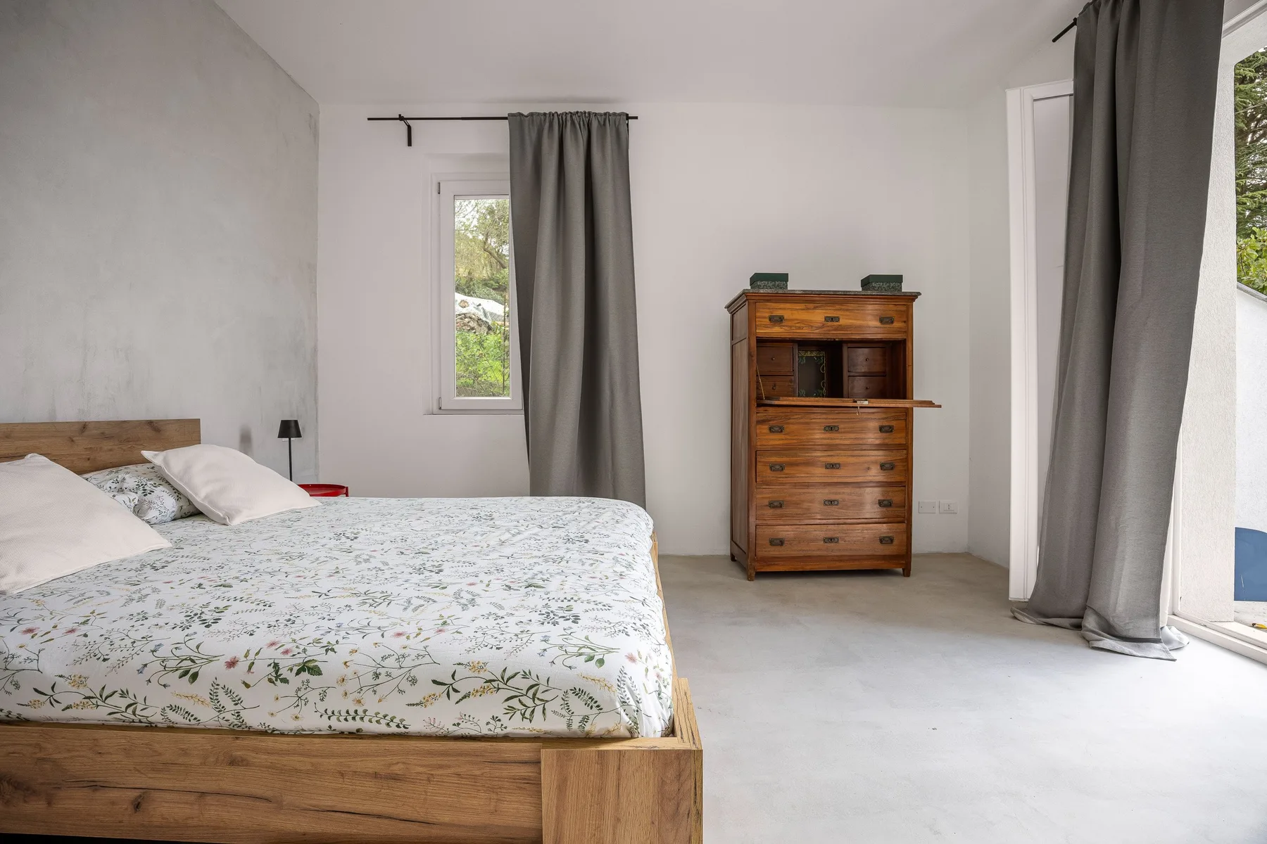 A bedroom with a wooden bed, patterned bedding, and a chest of drawers.
