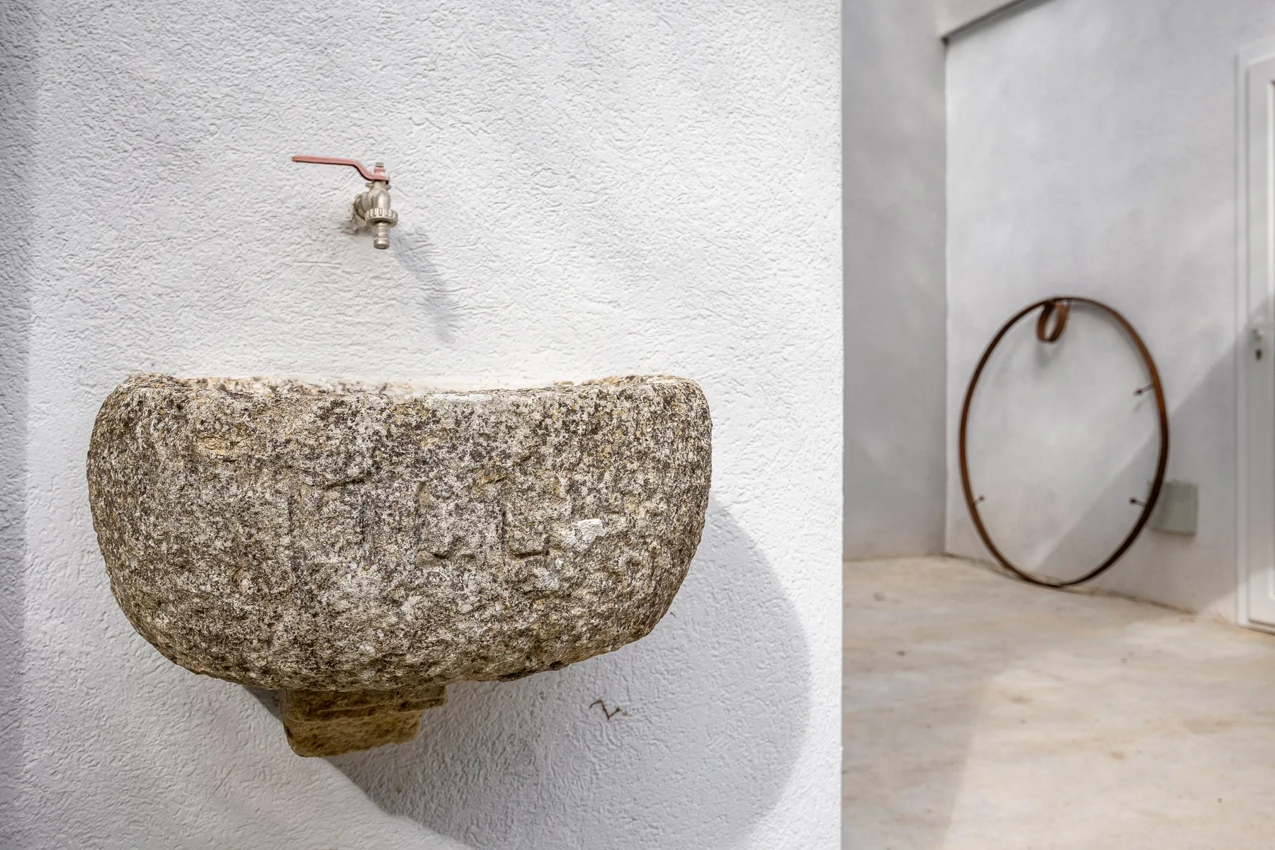 Un lavabo de piedra con grifo junto a una esquina interior despejada.