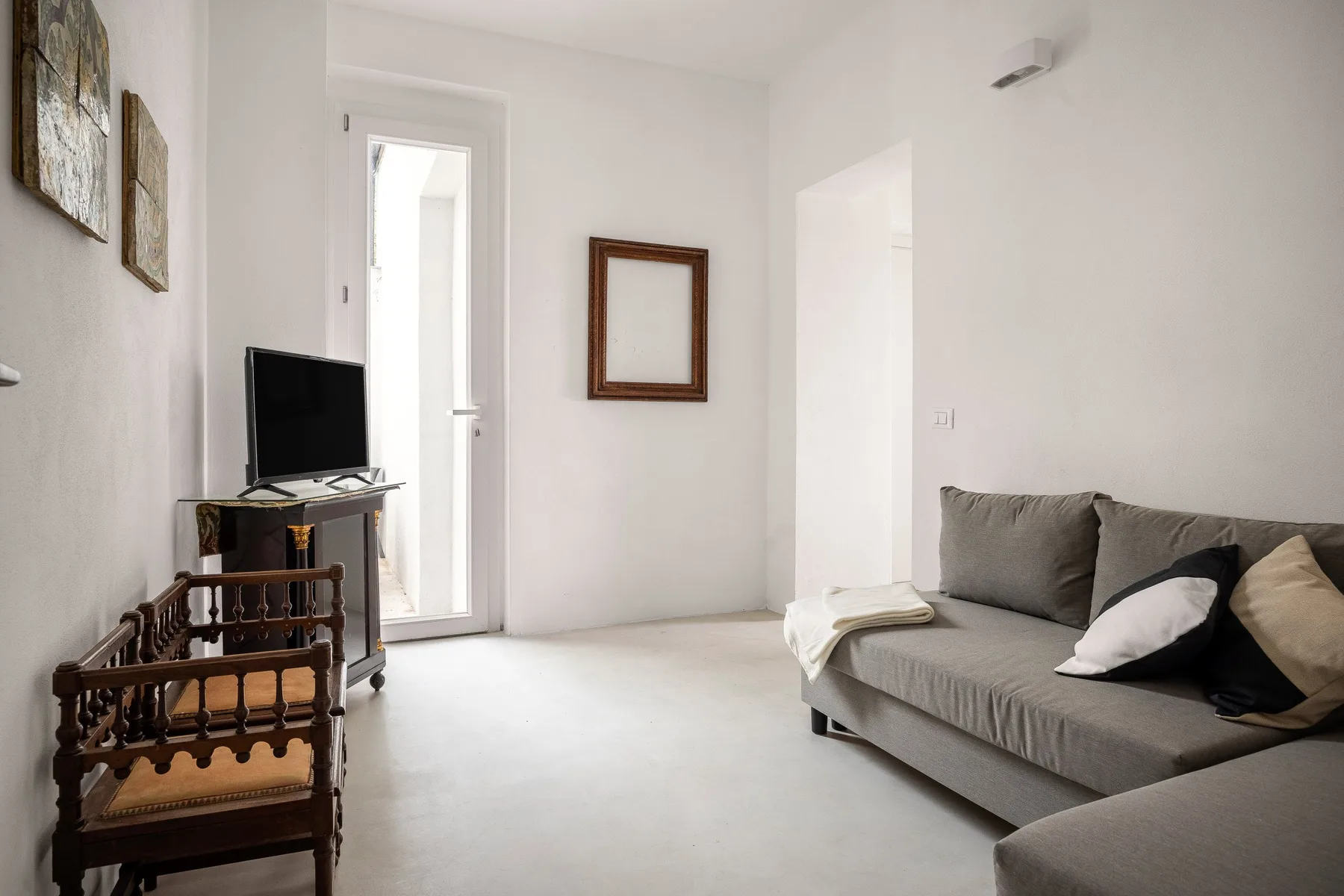 Una sala luminosa con un sofá gris y un televisor.