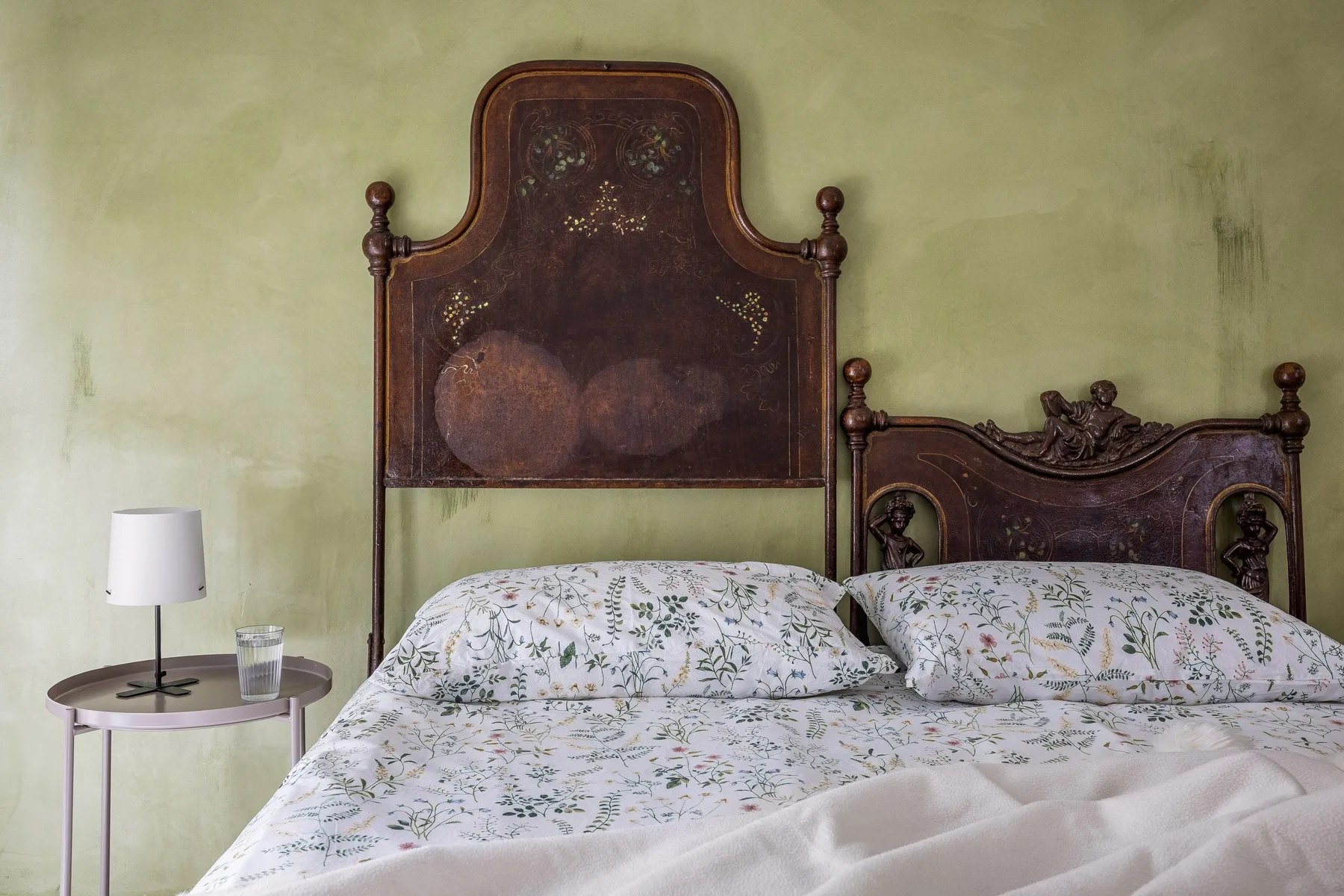 Un dormitorio con ropa de cama floral y cabeceros ornamentados de madera oscura.