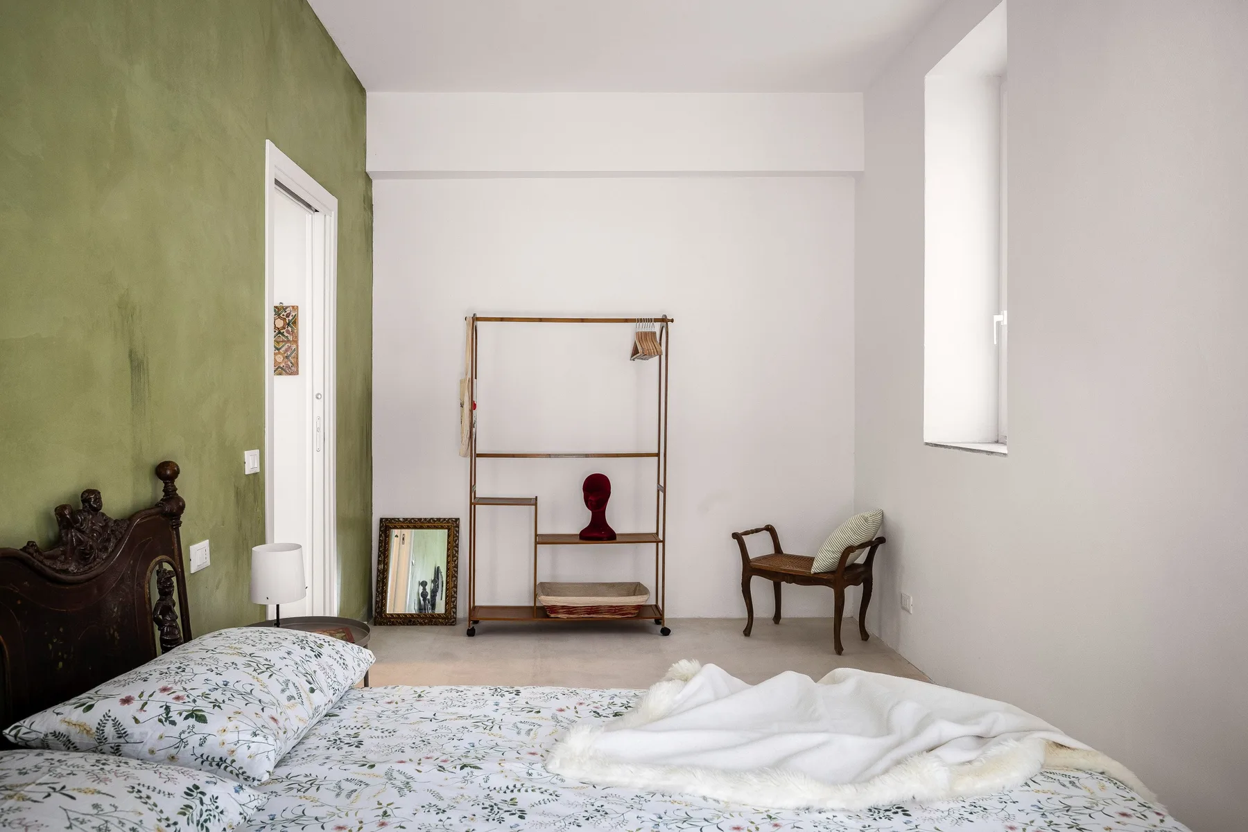 A bedroom with a patterned bed, a wooden rack, and a chair.