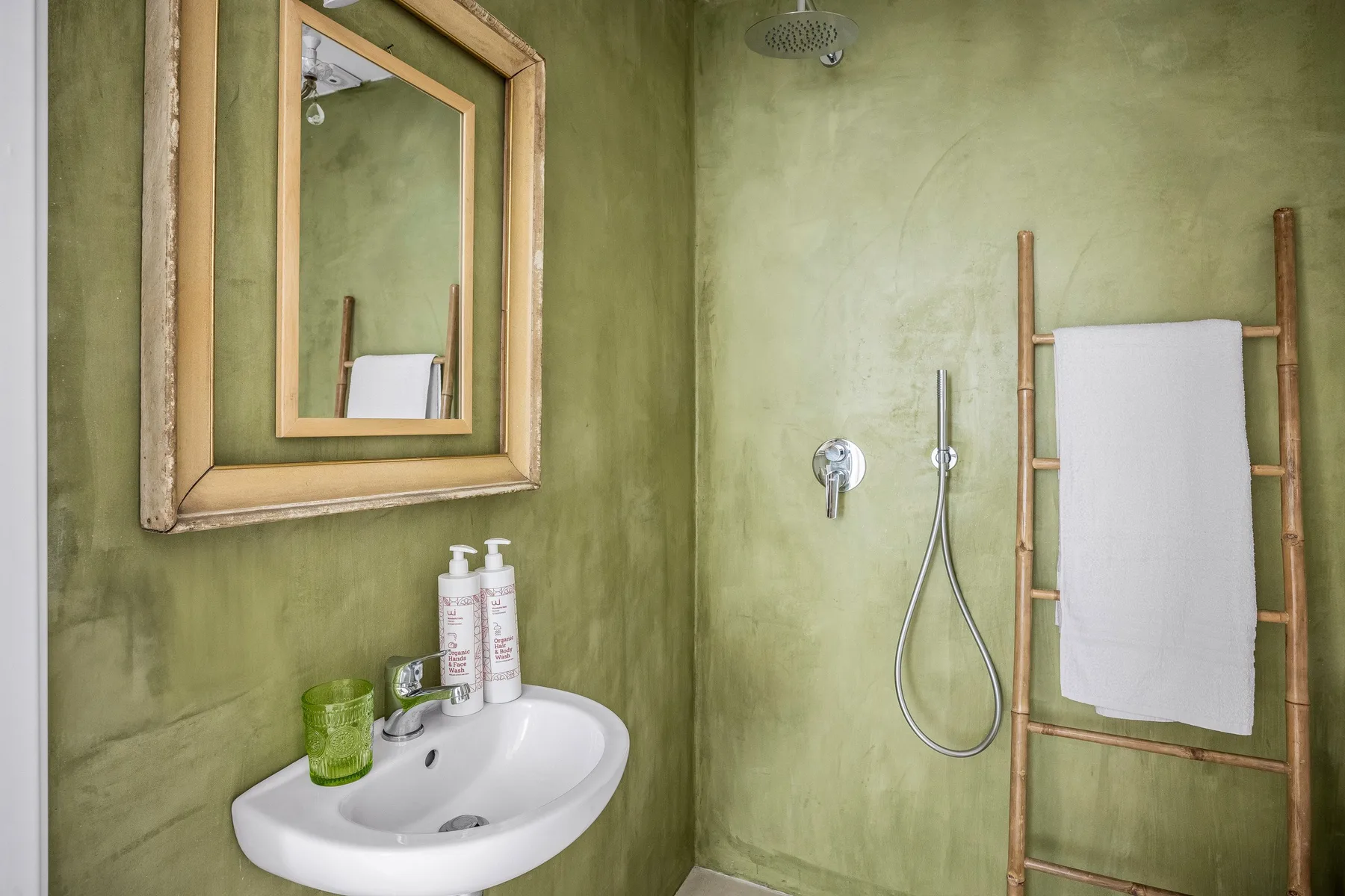 Un baño con lavabo, espejo de pared y una toalla colgada en un soporte.