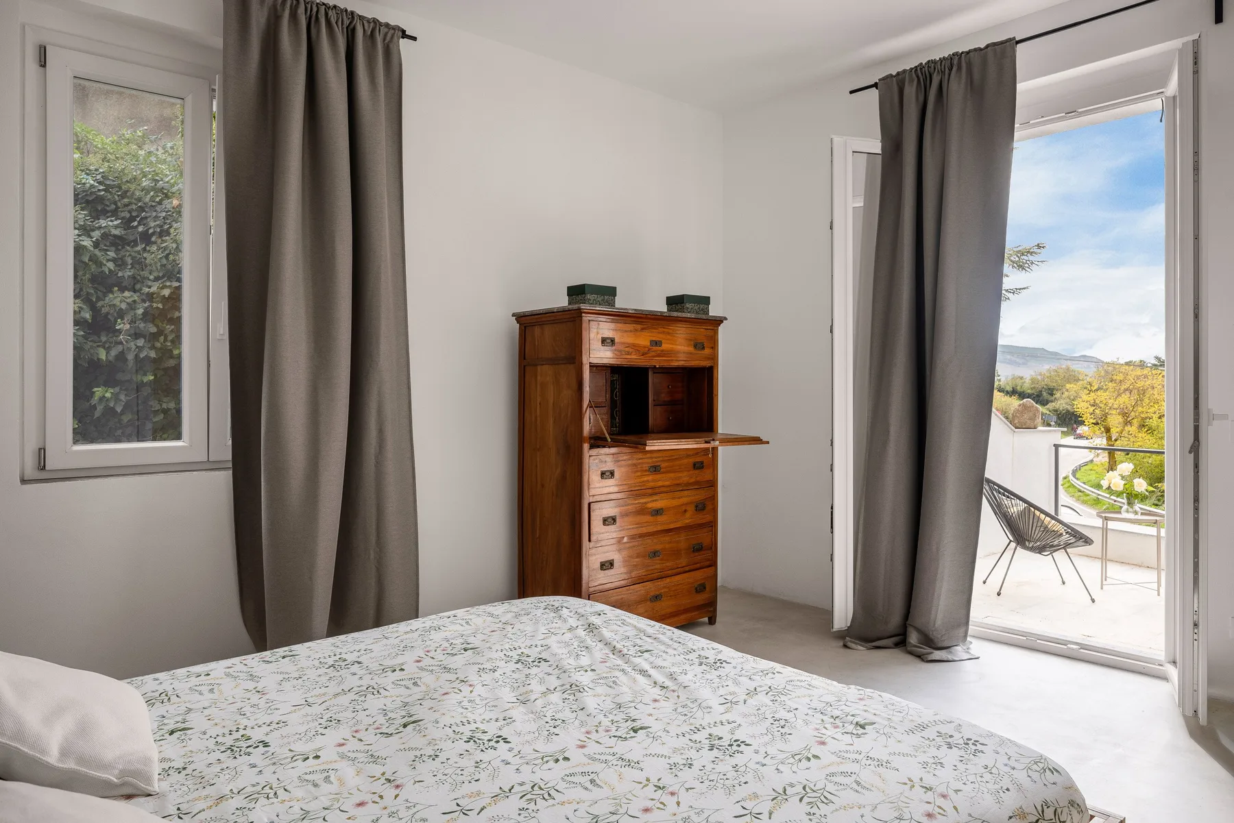 Dormitorio con una colcha estampada y una puerta abierta a un balcón.