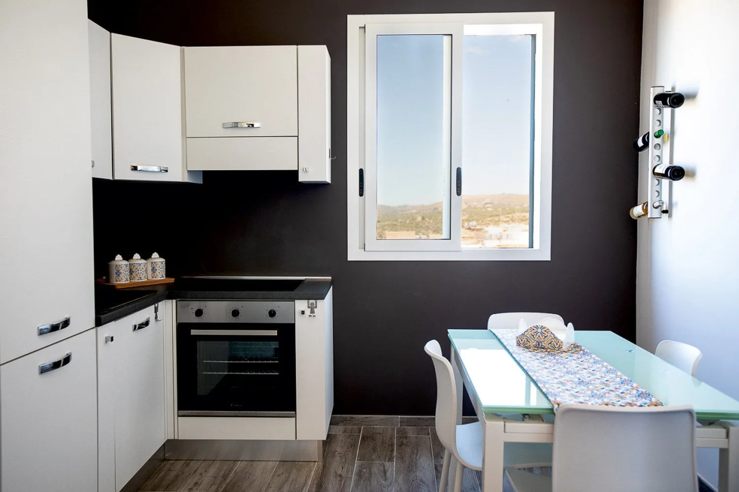 Una cocina moderna con comedor, armarios blancos y una mesa de vidrio.