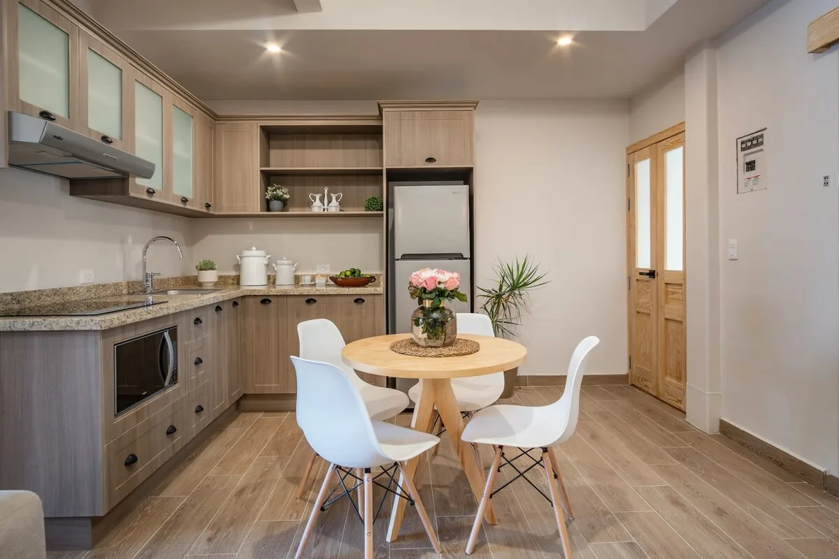 A kitchen and dining area with a round table and light-colored seating.