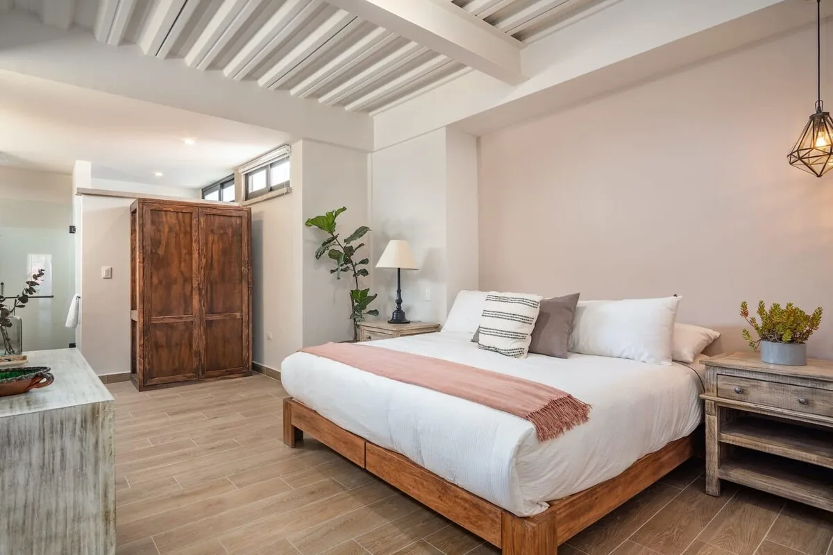 A bedroom with a wooden bed, white bedding, and a wooden wardrobe.