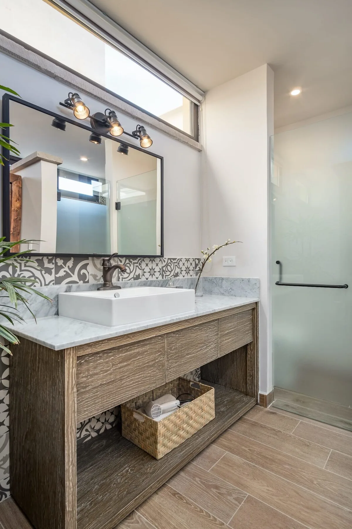A bathroom vanity with a sink and mirror beside a glass shower.