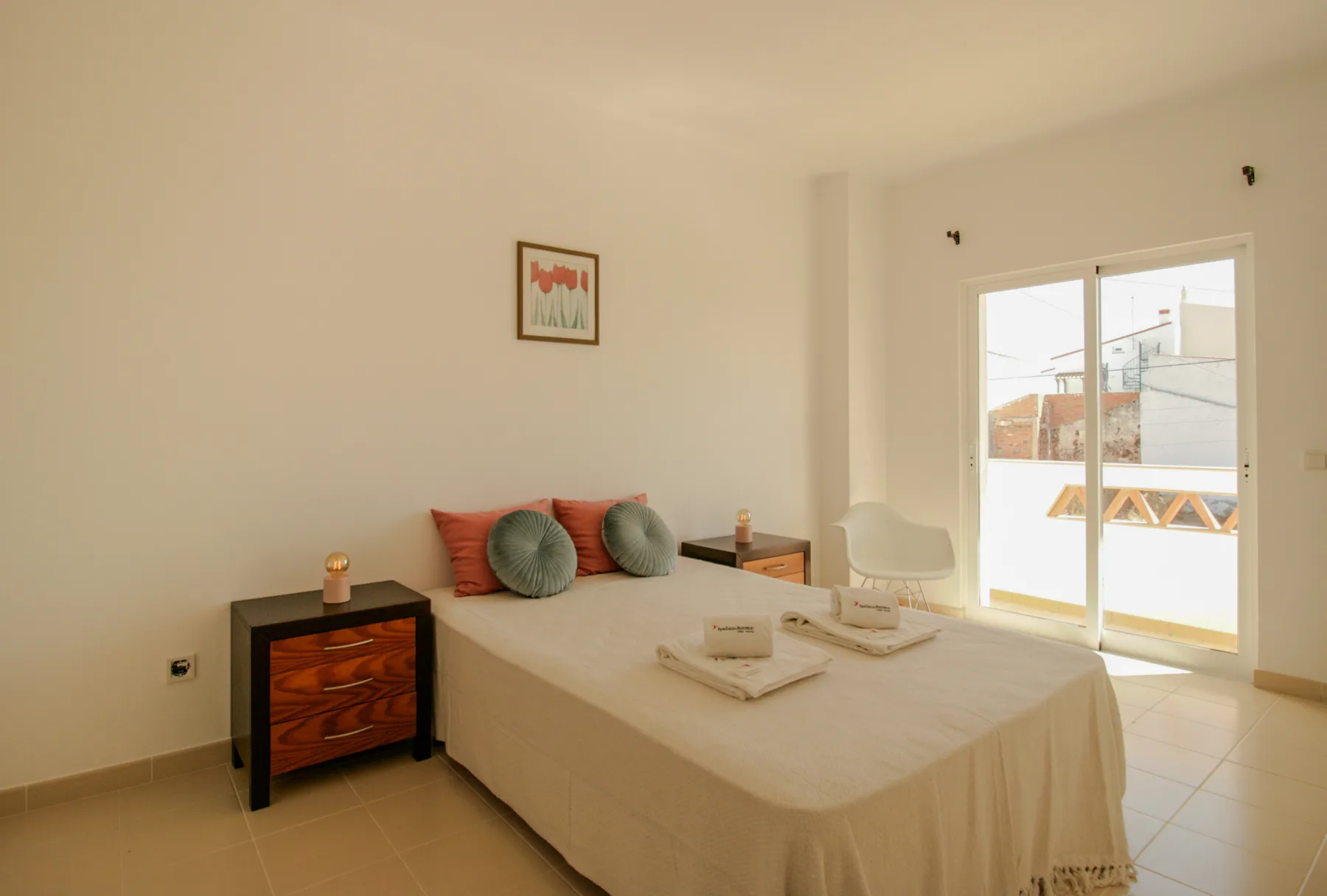 A bedroom with a bed, bedside table, and sliding glass doors to a terrace.