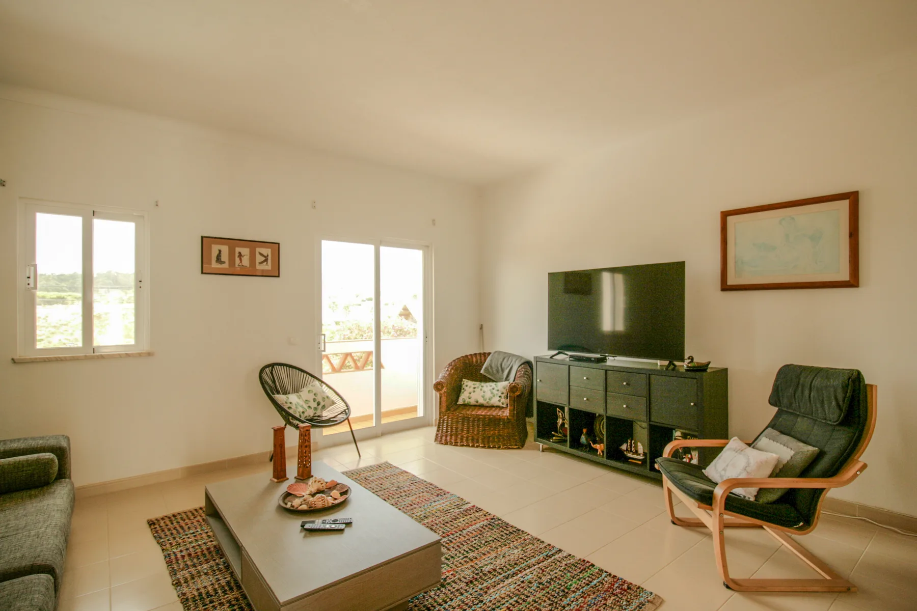 A bright living room with seating, a television, and sliding glass doors.