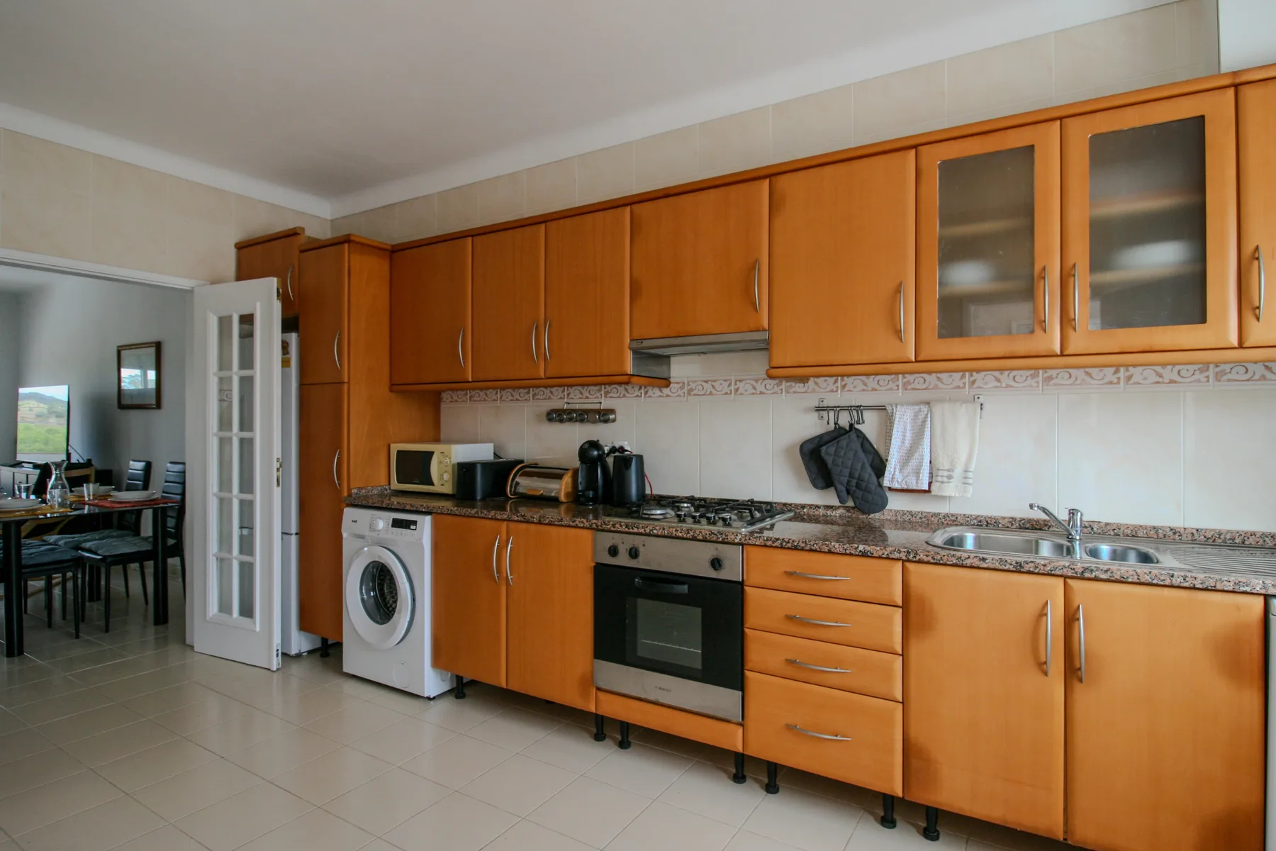 Una cocina con armarios de madera, una encimera y una lavadora.
