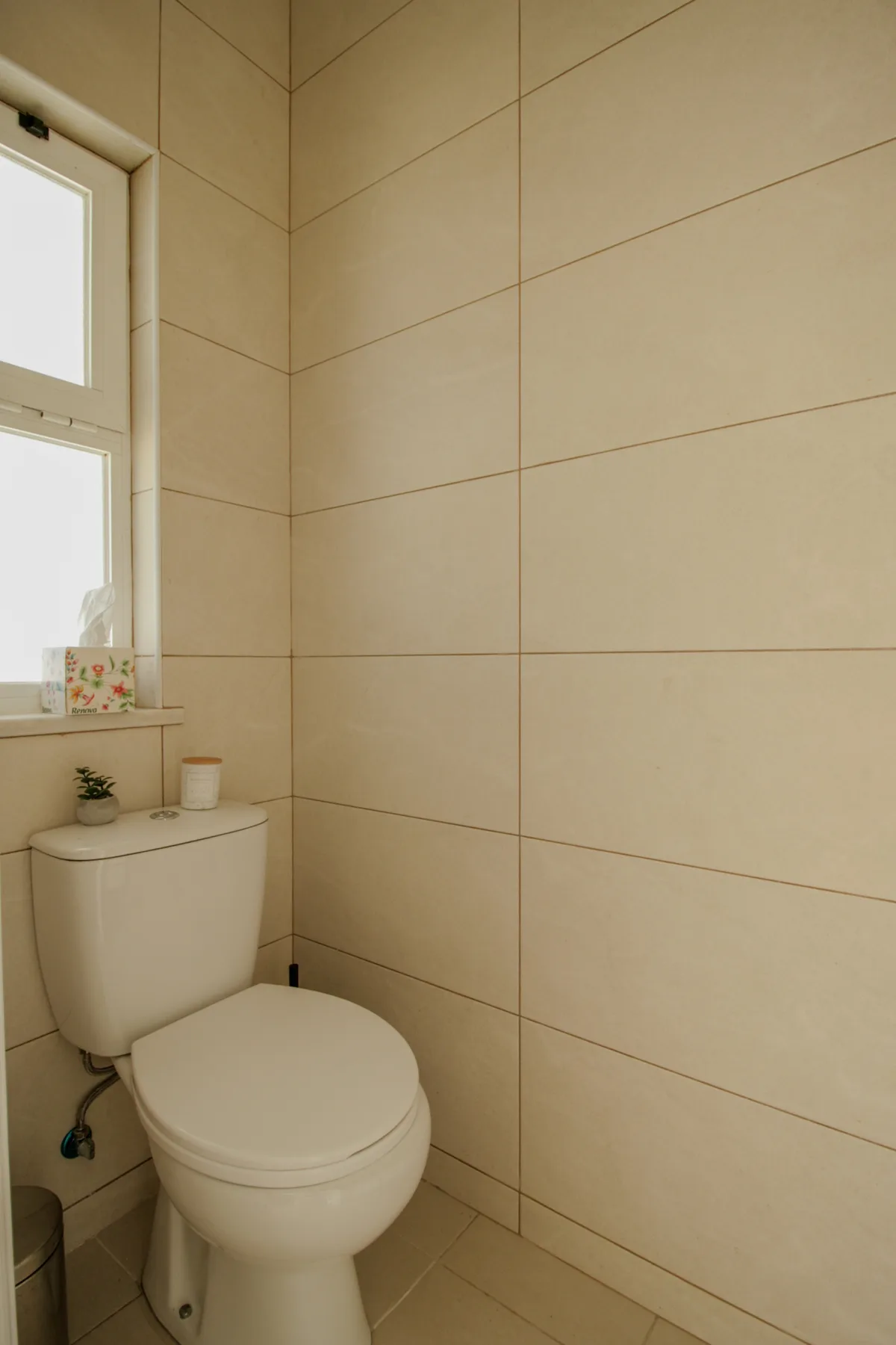 Un baño con un inodoro debajo de una ventana.