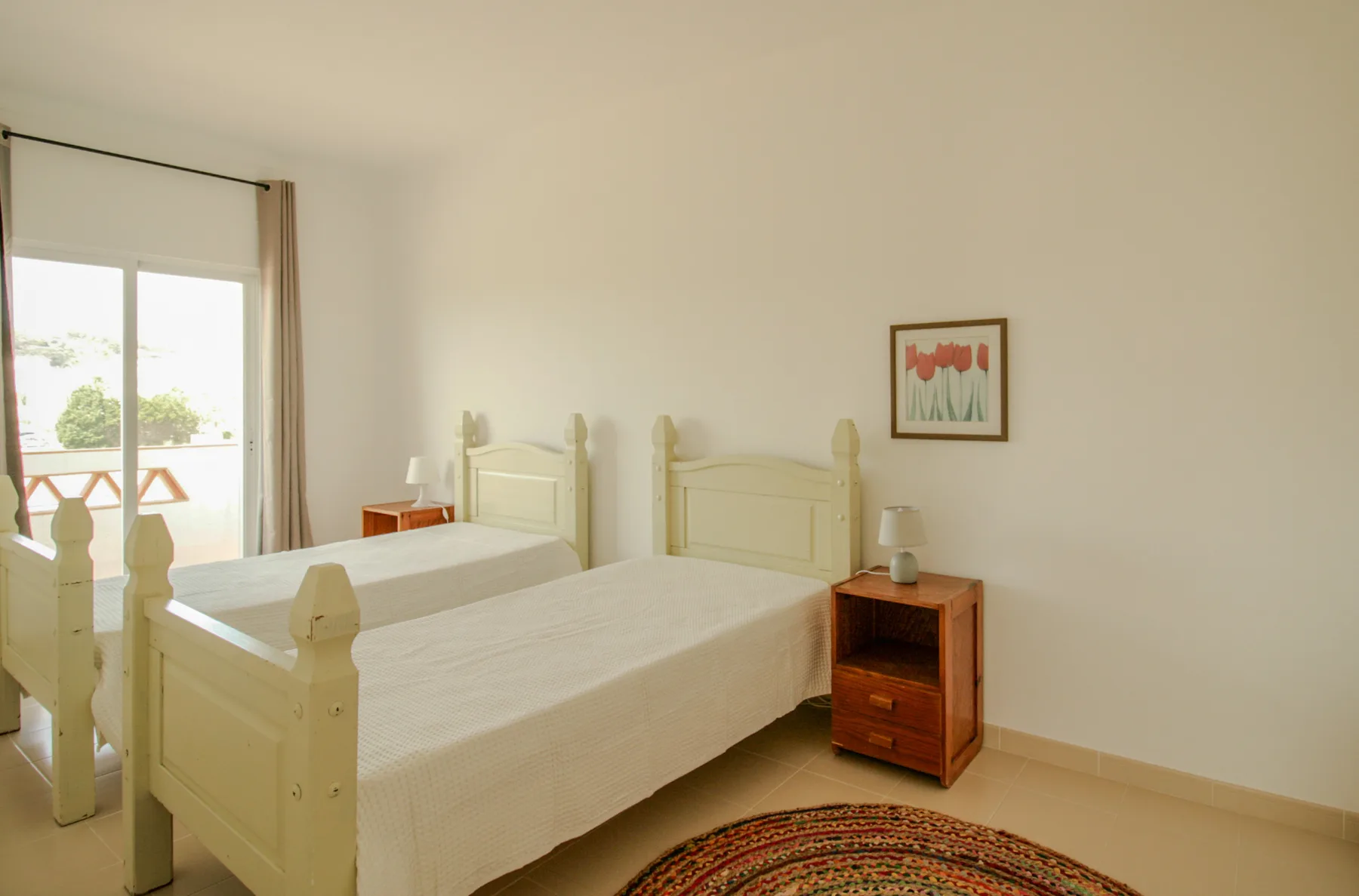 A bedroom with two beds and a balcony door.
